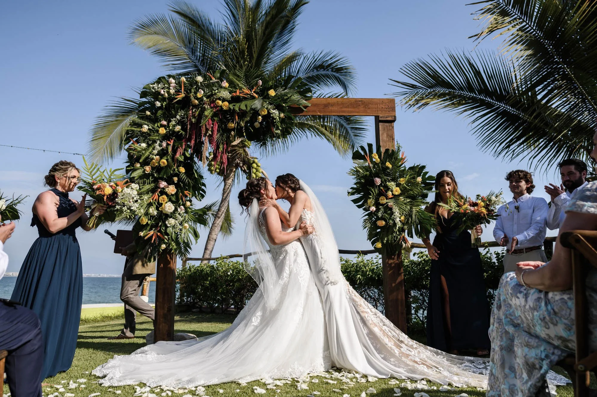 Lesbian brides kissing at end of ceremony at an outdoor beach wedding in Puerto Vallarta. 
