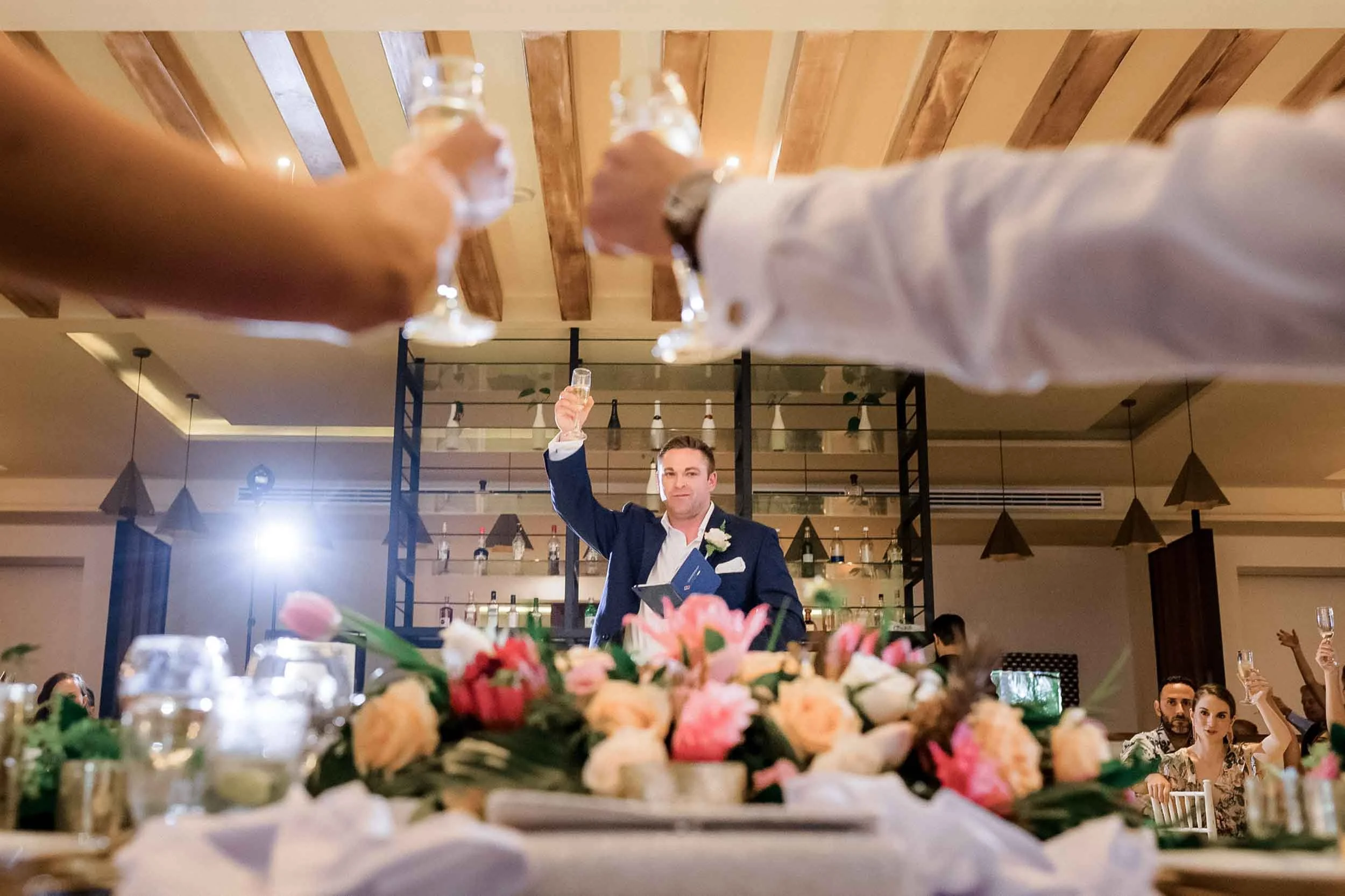 Bride and groom toasting with best man during reception dinner.