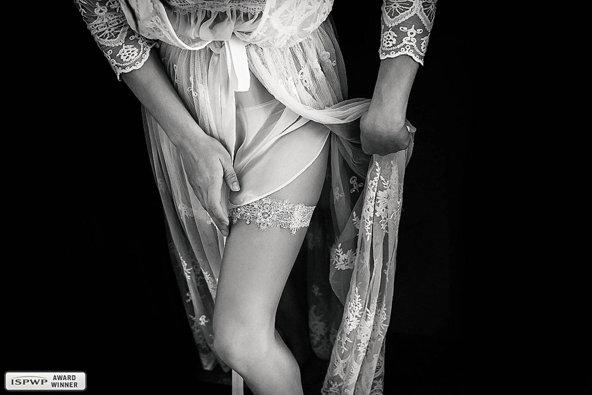 Detail shot of garter and lace robe of bride getting ready on her wedding day.