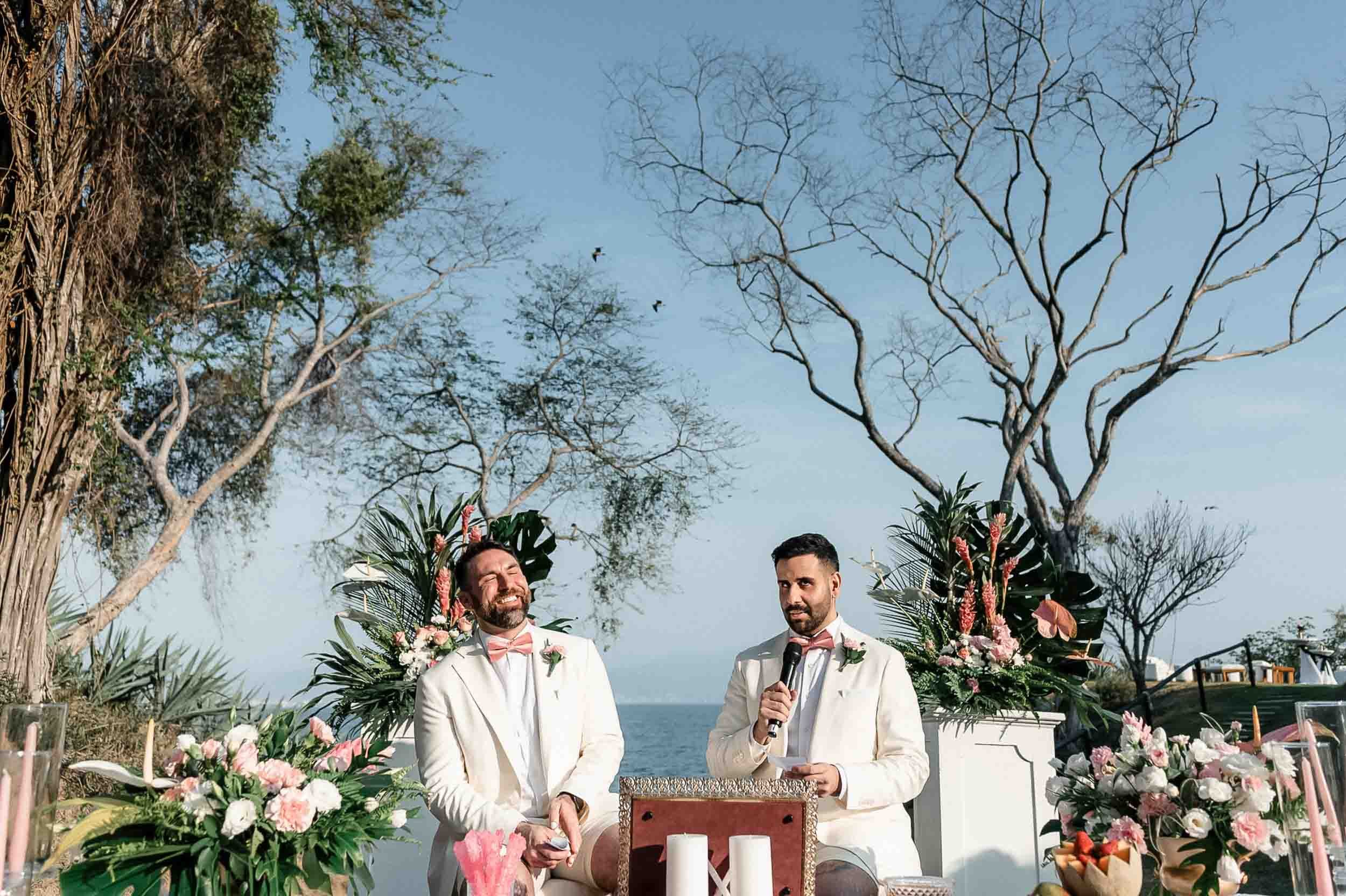 Grooms reading their vows during their Persian wedding in a beach setting in Puerto Vallarta 