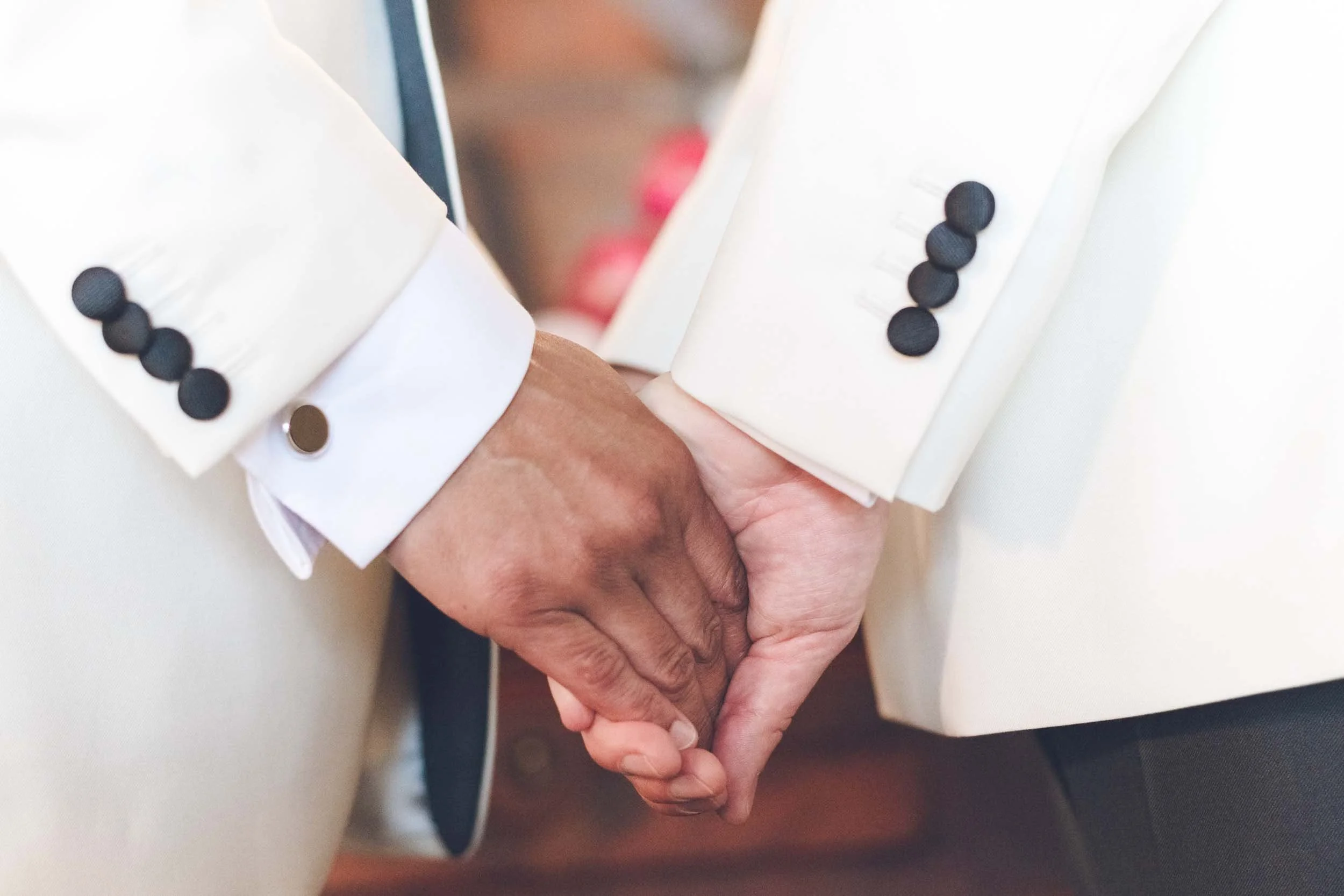 Close-up of two grooms holding hands, before leaving towards their destination wedding ceremony.