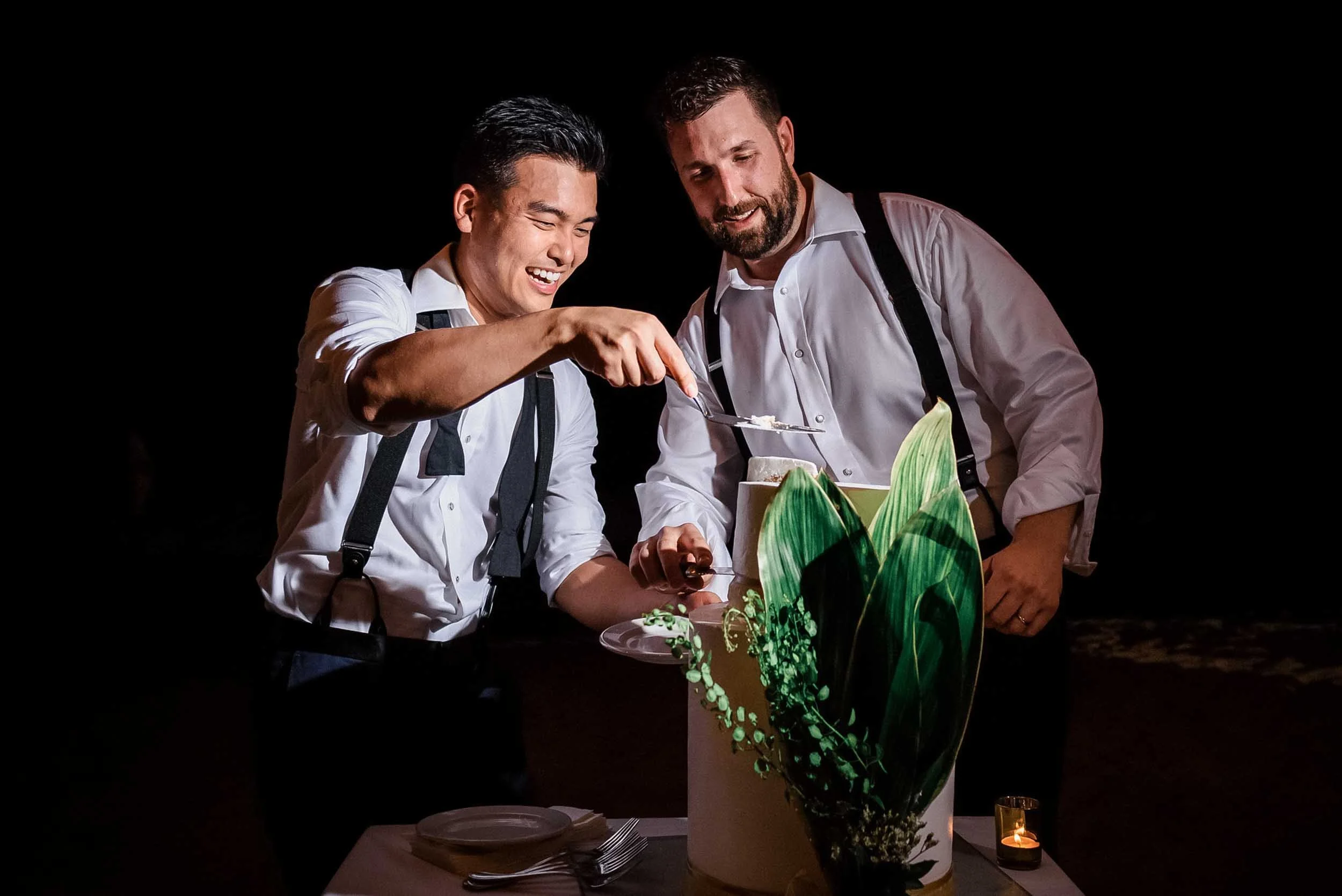 Grooms cutting their wedding cake during their beach wedding celebration.