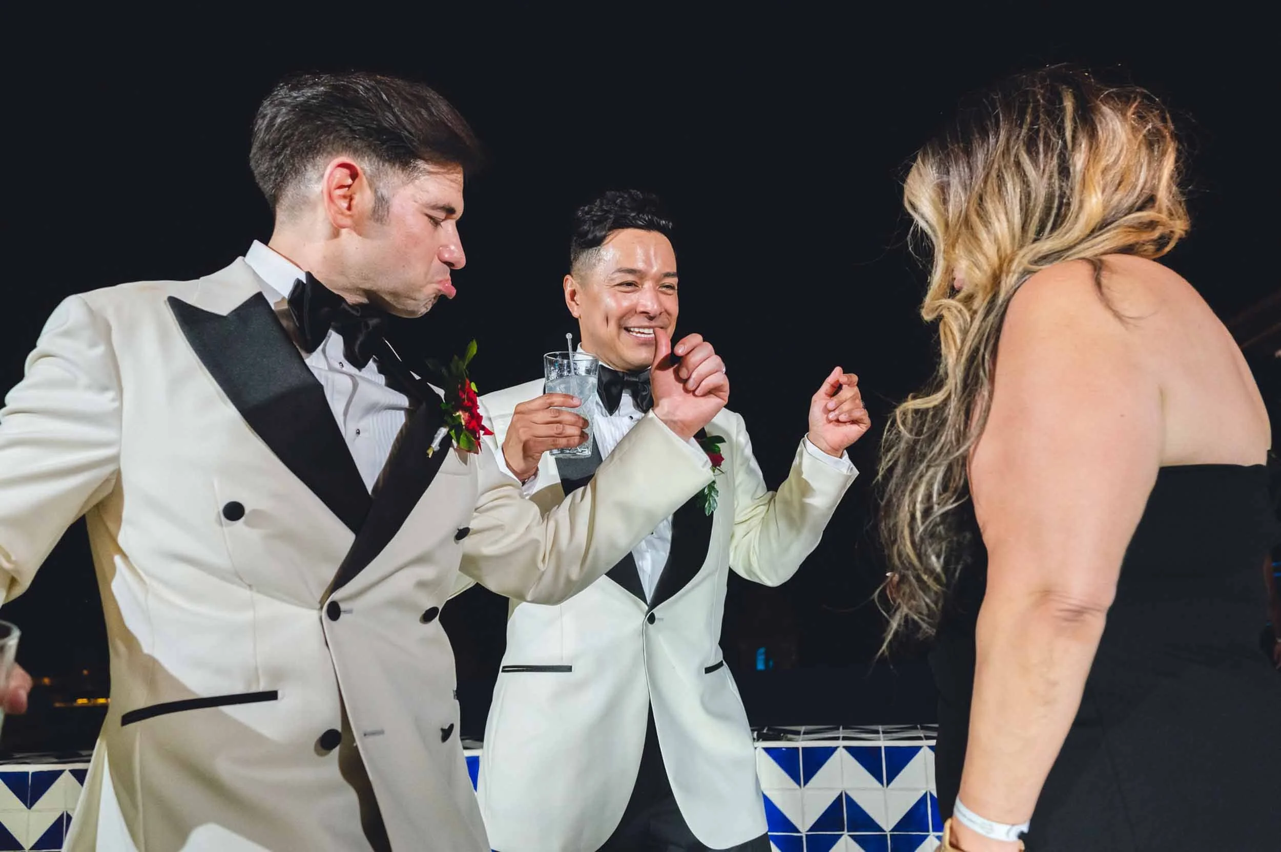 Grooms on dance floor dancing during their outdoor wedding reception, along with other guests. 