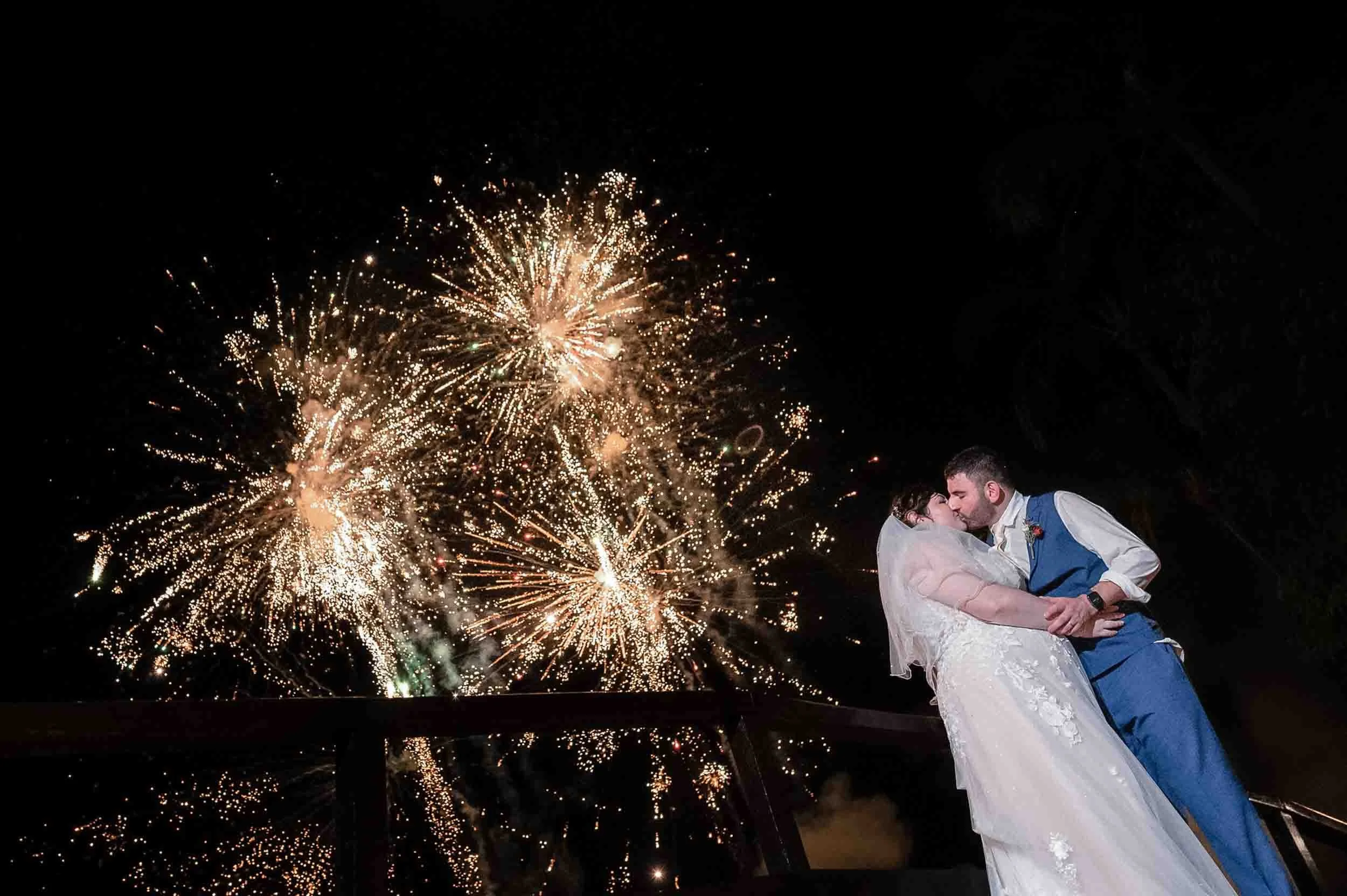 Bride and groom sharing a kiss under fireworks at night at the Hyatt Ziva resort.