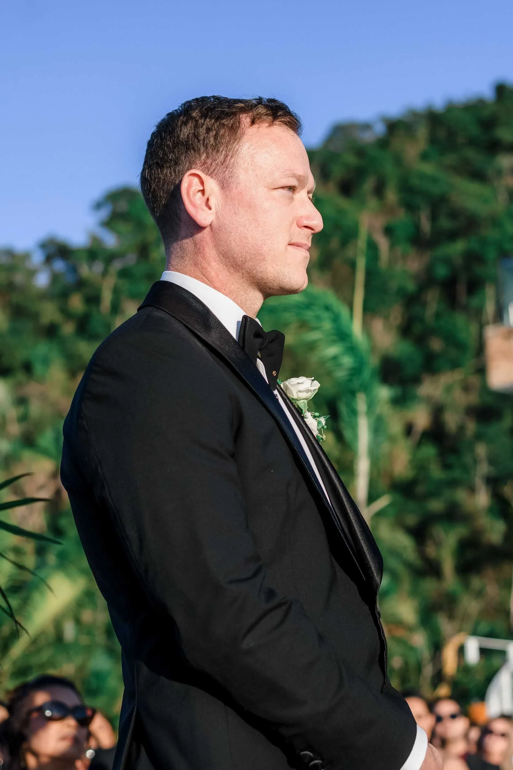 Groom during his wedding ceremony standing while the other groom reads his wedding vows.