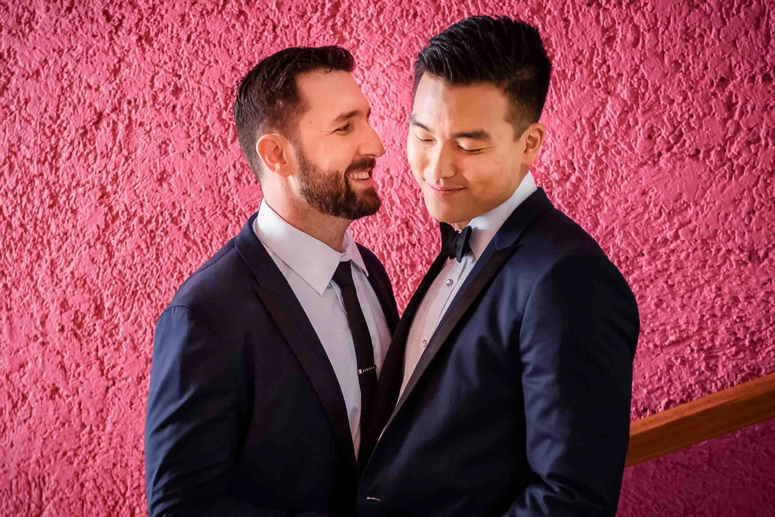 Grooms smiling and leaning their foreheads together posing for photos.