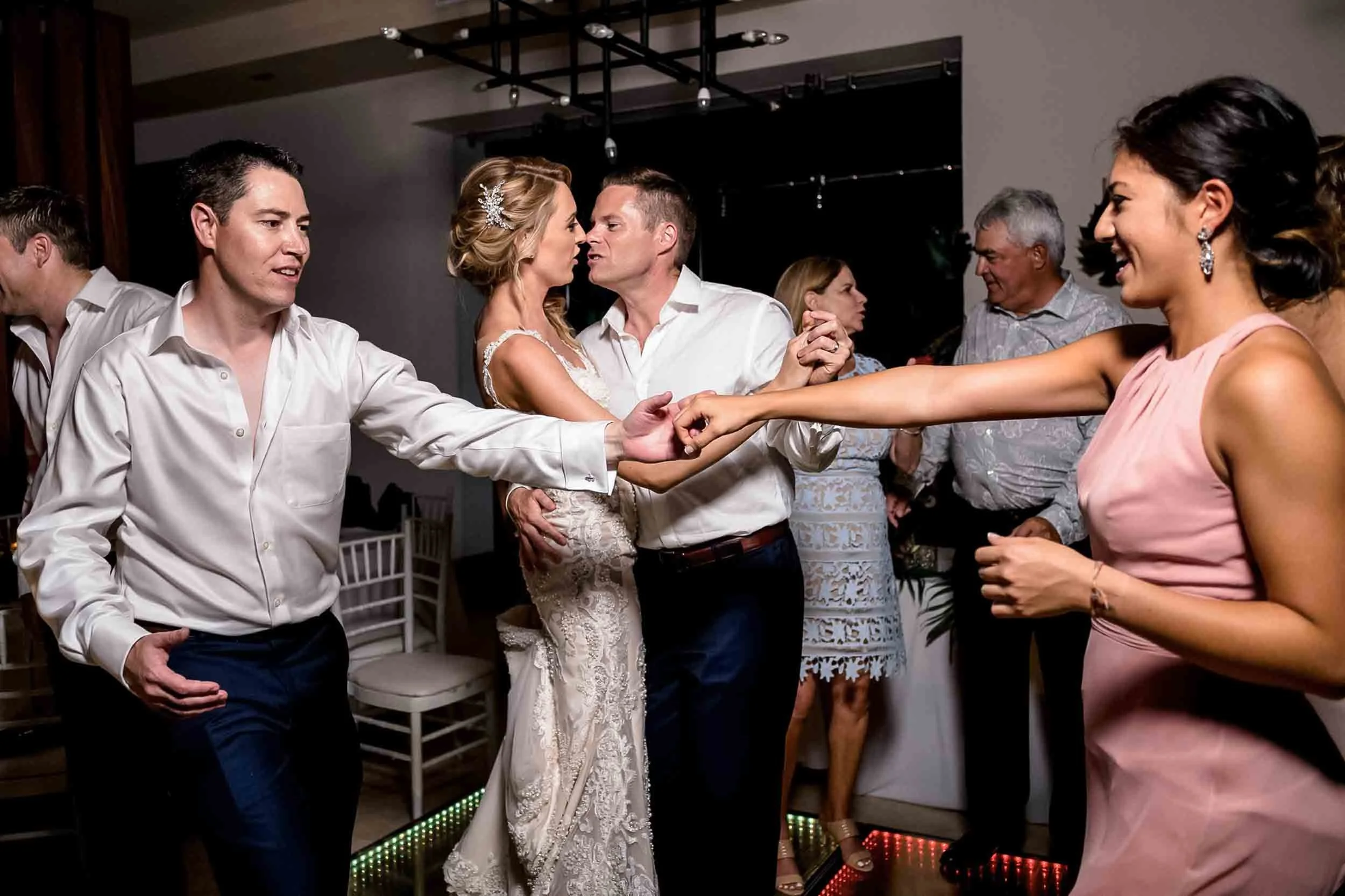 As a couple dances bride and groom kiss in the background during their wedding reception.