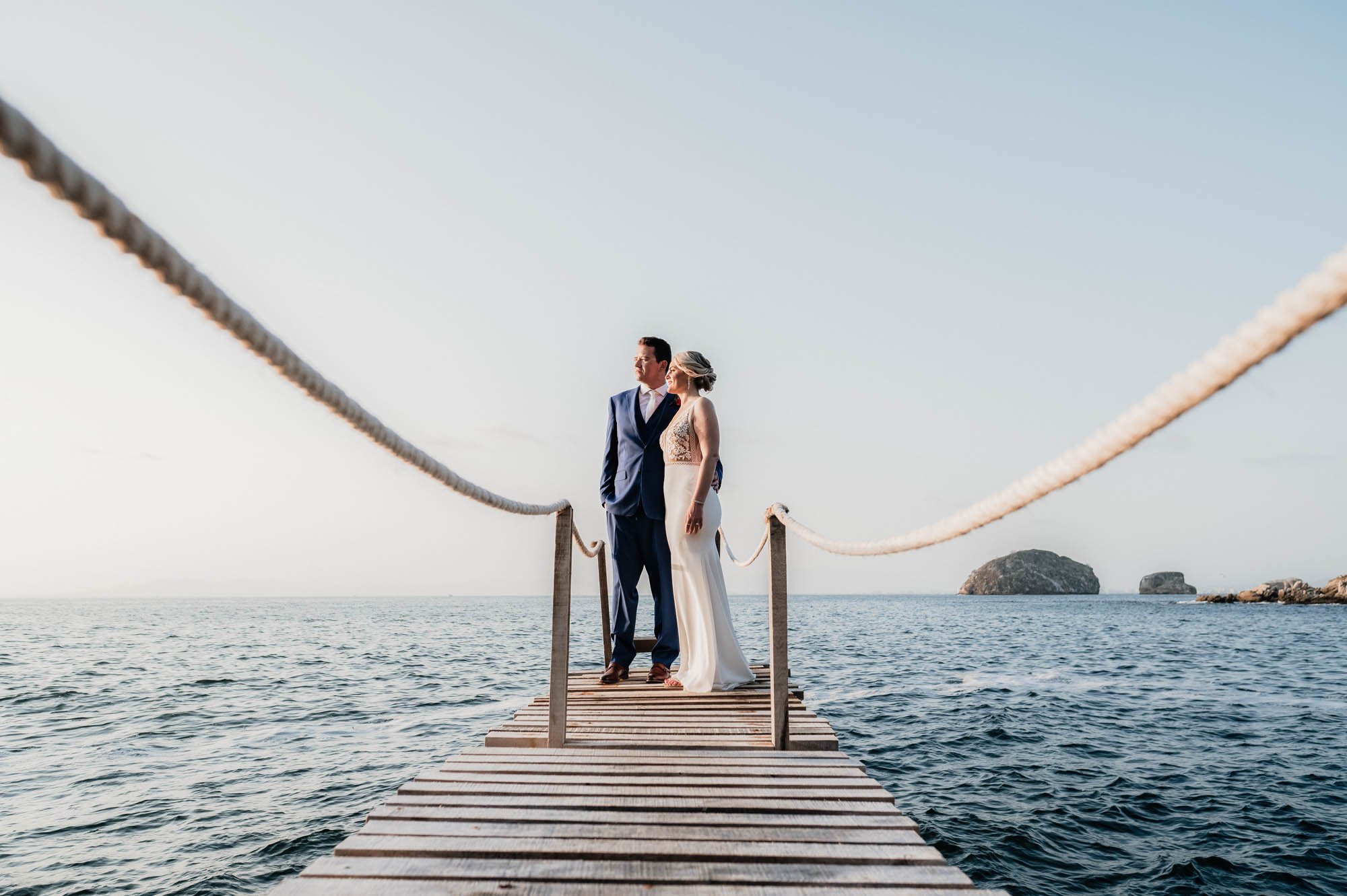 Bride and groom posing at private dock with beautiful blue ocean and Los Arcos in the background. 