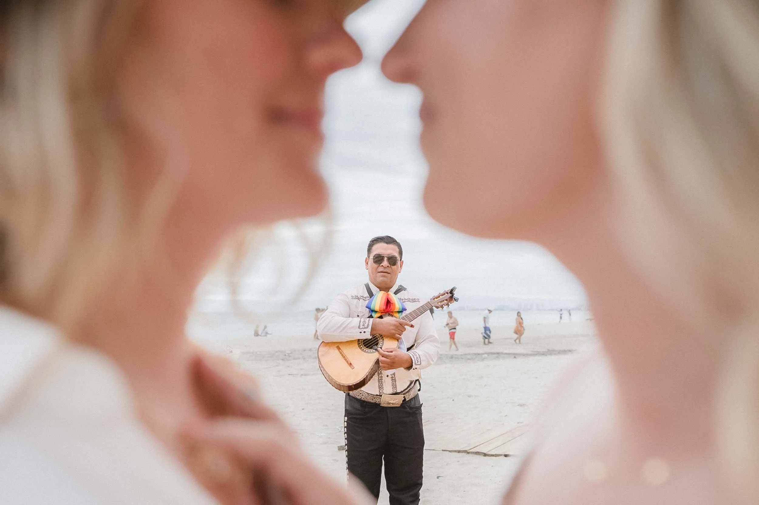 Mariachi looking at lesbian couple at beach in Puerto Vallarta