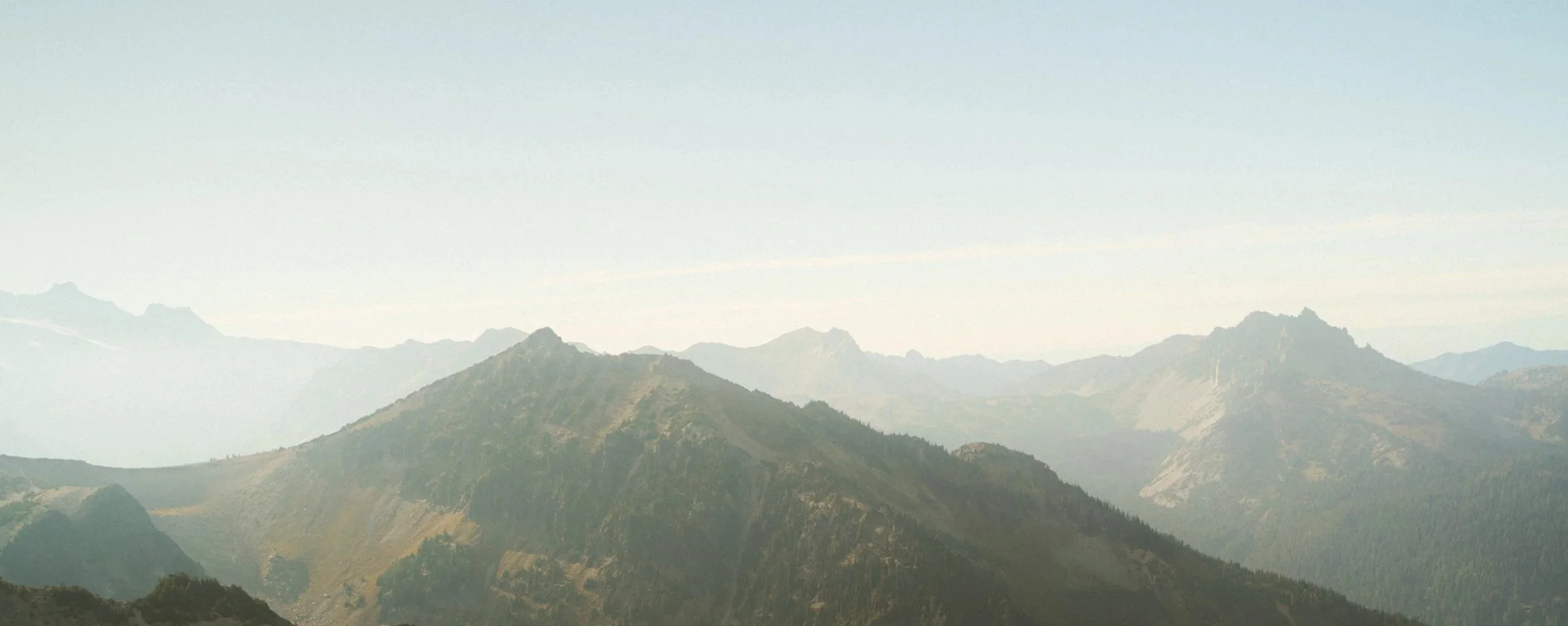 Scenic view of mountain range with multiple peaks and ridges under a clear sky.