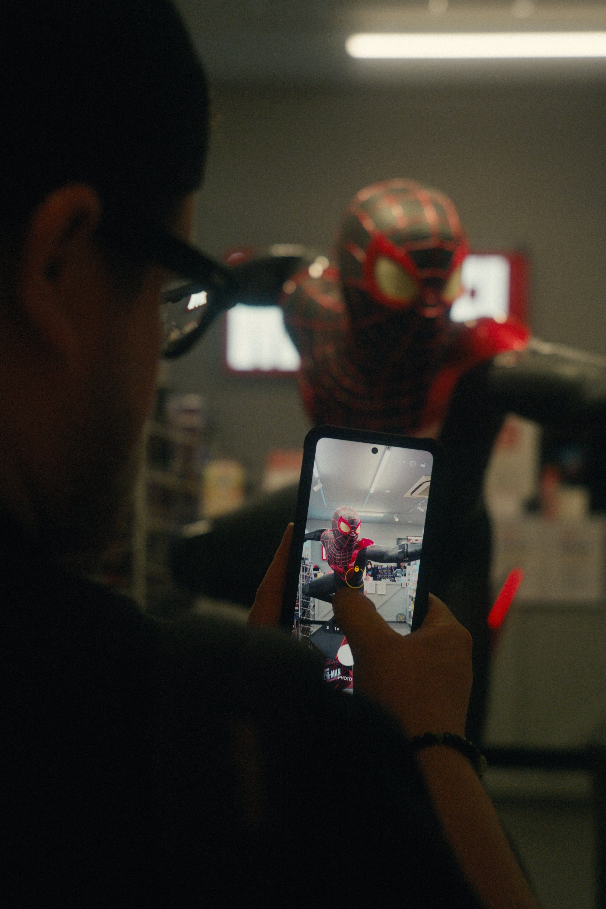 A person taking a photo of a Spider-Man action figure with a smartphone in a store.