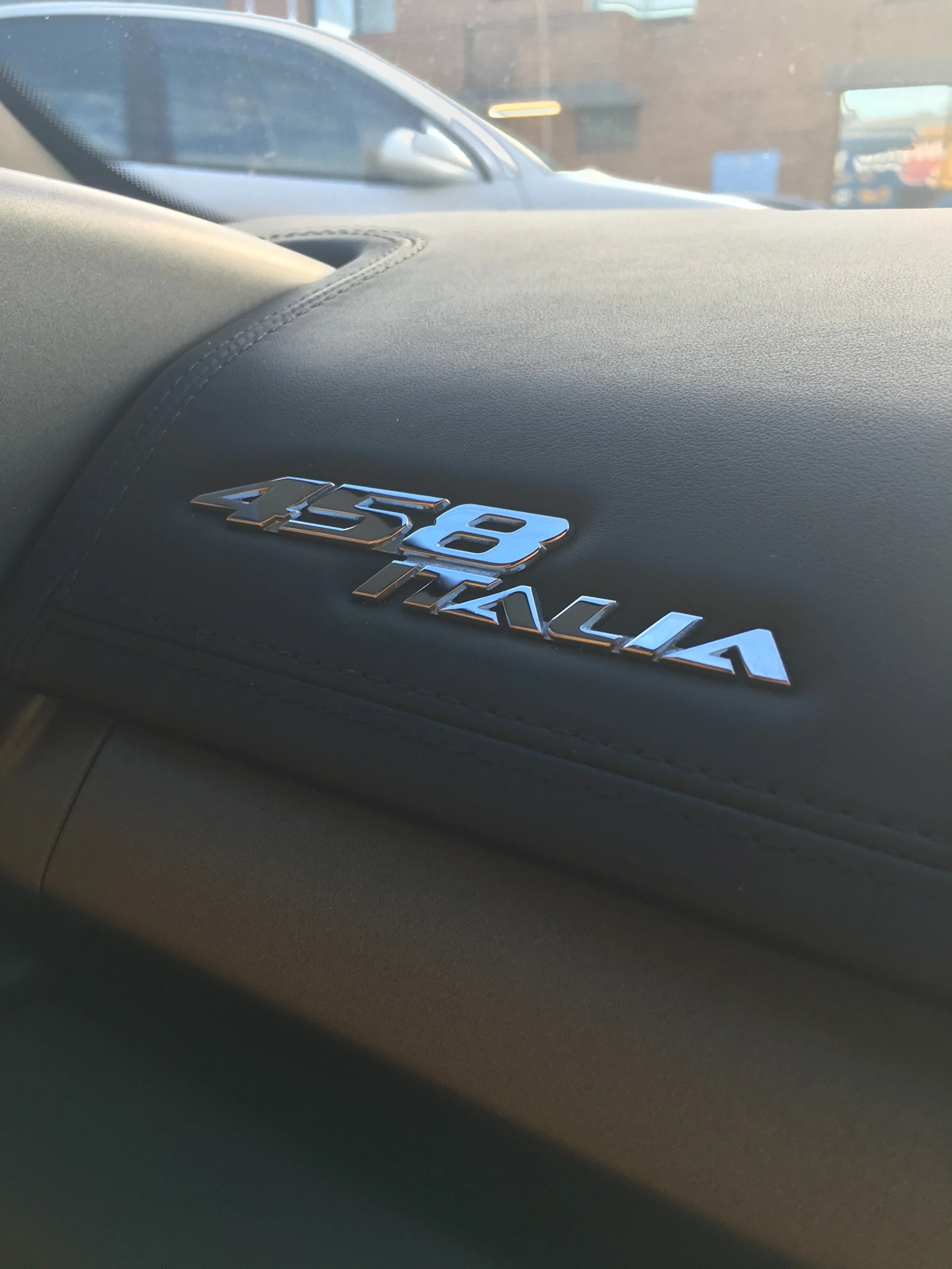 Close-up image of a black car dashboard with a silver Mitsubishi logo on it.