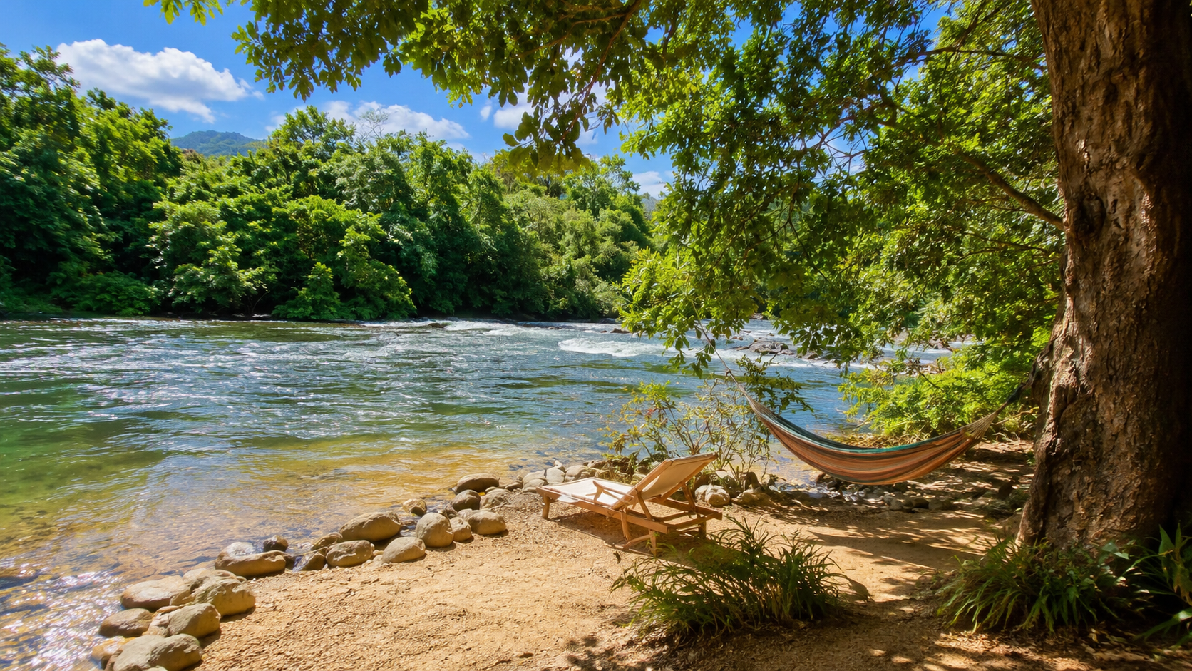 Plage ombragée avec hamac et chaise longue près d'une rivière entourée d'arbres verts, ciel bleu ensoleillé.