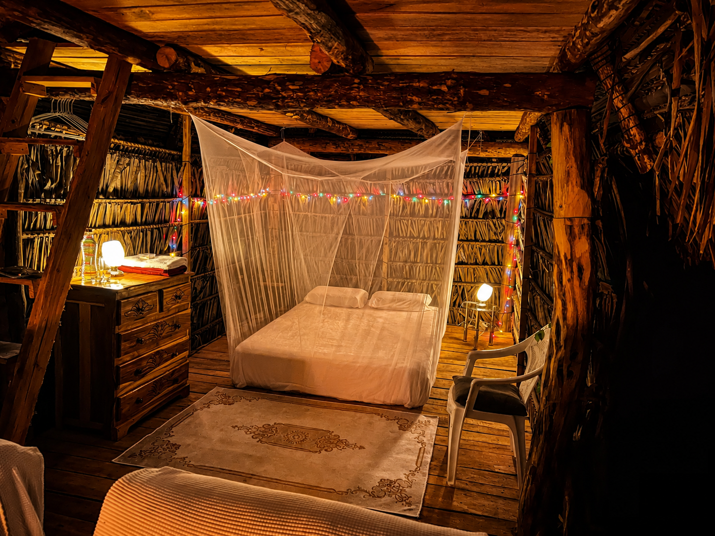 Chambre romantique dans une cabane avec lit avec moustiquaire, décorée de guirlandes lumineuses, meubles en bois, tapis beige, et un éclairage chaleureux.