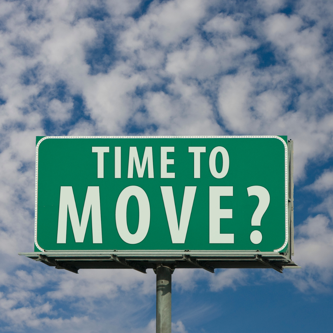Green highway sign with the message "Time to move?" against a partly cloudy sky.
