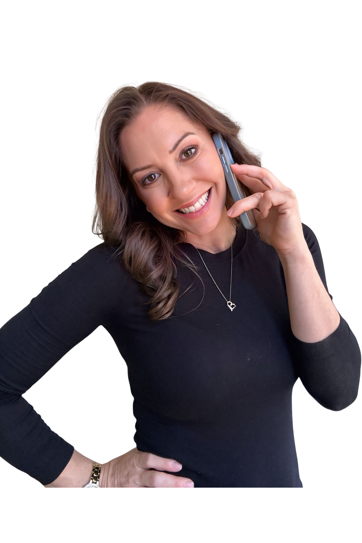 A smiling woman with brown wavy hair, wearing a black long-sleeve shirt, a necklace with a heart pendant, a gold watch, and a bracelet, talking on a cell phone.
