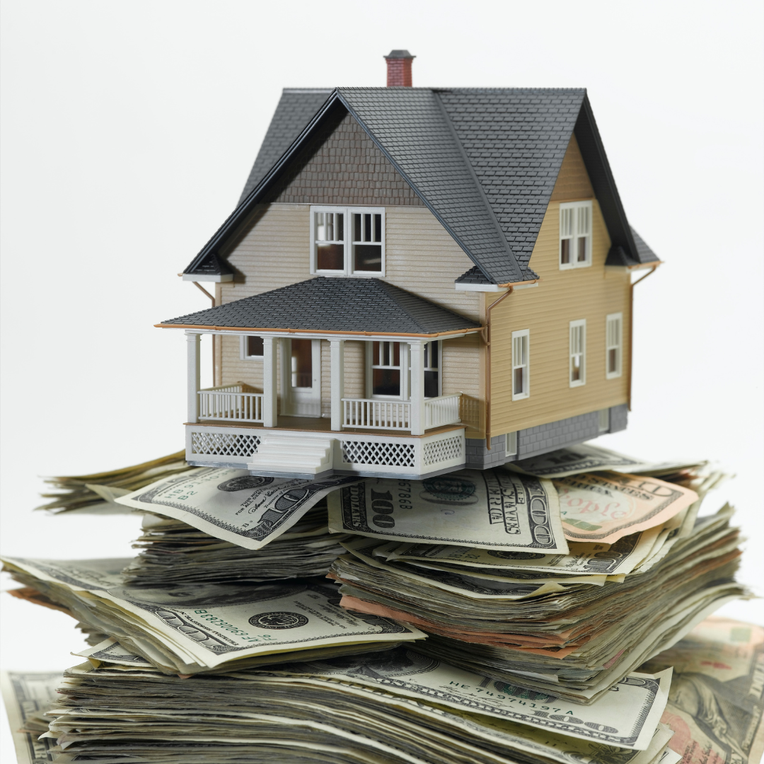 A model house placed on a large pile of US dollar bills.