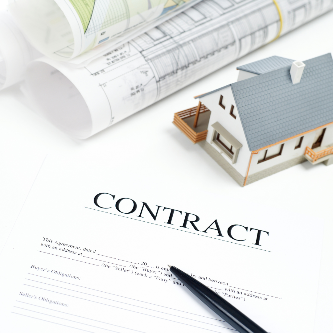 A real estate contract form, a black pen, a small model house, and architectural blueprints on a white surface.