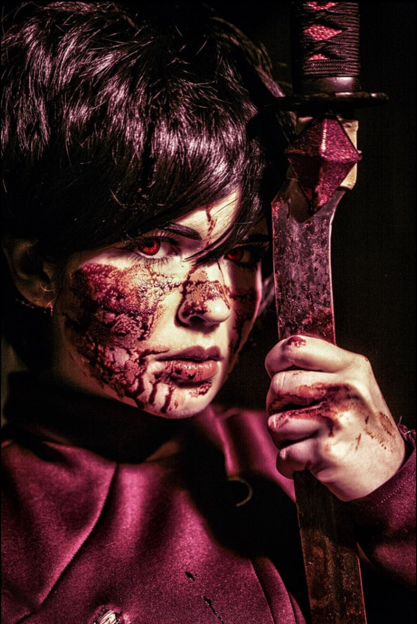 A person with dark hair, glowing red eyes, and a face painted to resemble cracked scars, holding a blood-stained machete, wearing a maroon hoodie, in a dark setting.