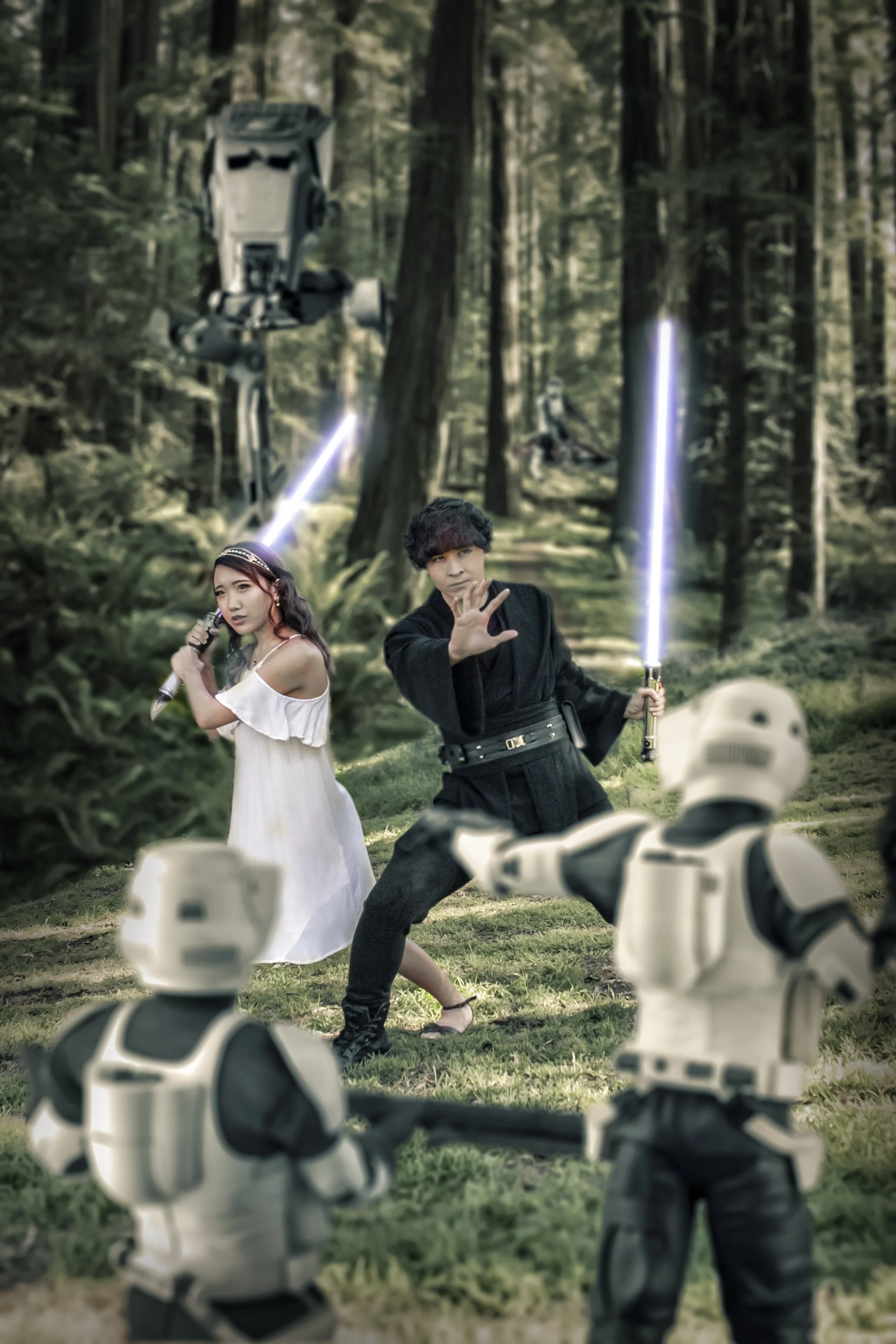 Two people dressed as Star Wars characters, a young woman and a man, perform a scene with lightsabers in a forest. Two stormtroopers are in the foreground, partially visible.