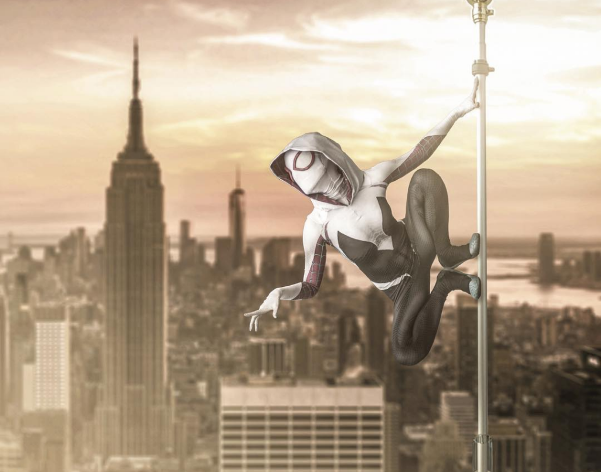 A person dressed as Spider-Gwen hanging from a flagpole on a city rooftop with the Empire State Building in the background during sunset.