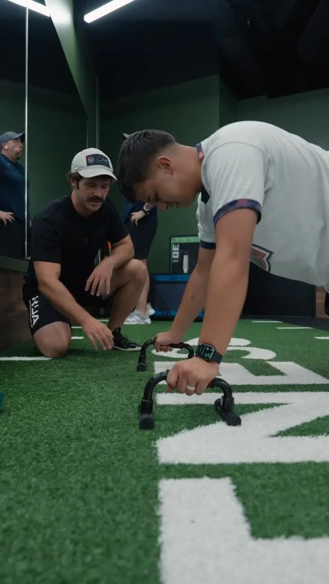 Personal Trainer Taylor Smith coaching a client through push‑ups on turf inside Haus of Fitness in Oceanside, San Diego.  
Taylor provides hands‑on form correction, strength progression, and individualized training during every session.