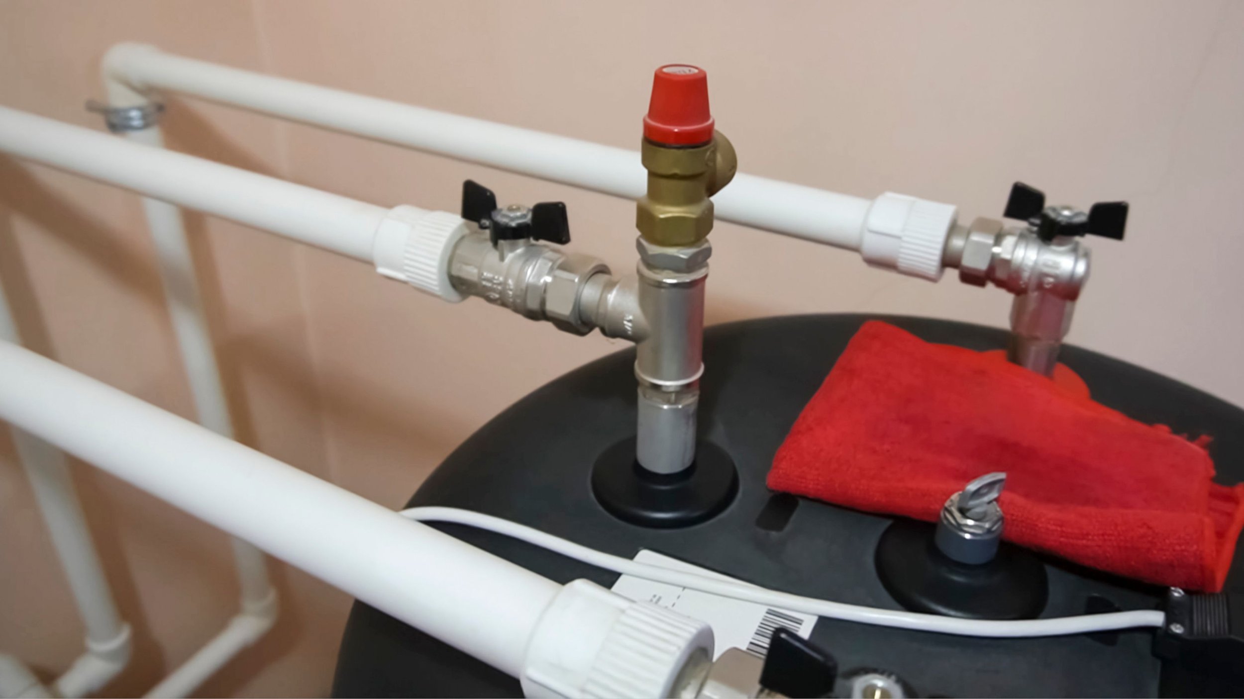 Pipes and valves connected to a black tank, with a red cloth draped over part of the tank.