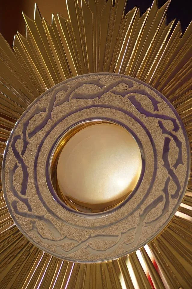 Vista desde abajo de un recipiente decorativo dorado con un diseño intrincado, rodeado de rayos dorados que irradian hacia afuera.