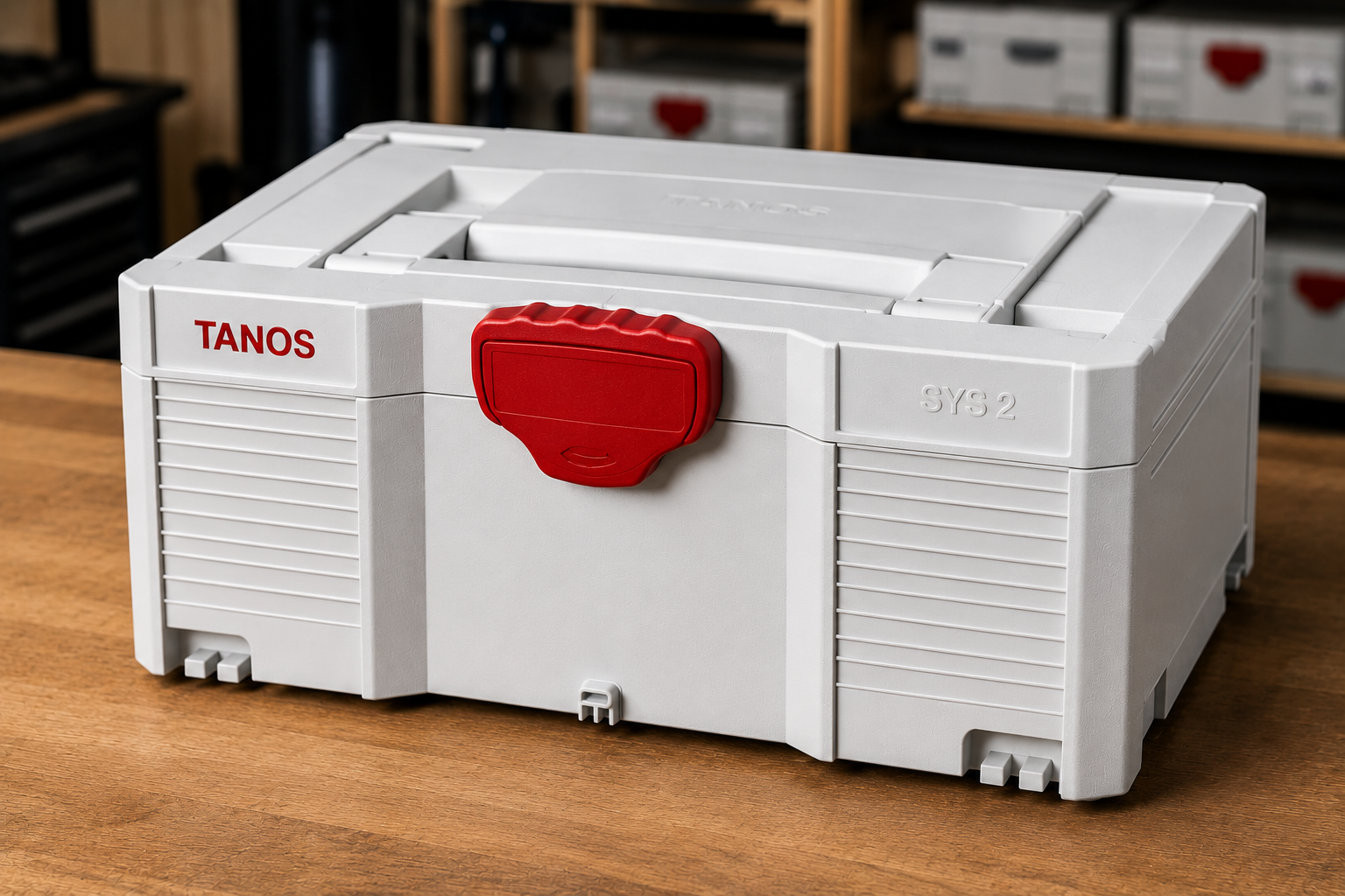 A white plastic toolbox with a red latch, labeled TANOS, sitting on a wooden surface.
