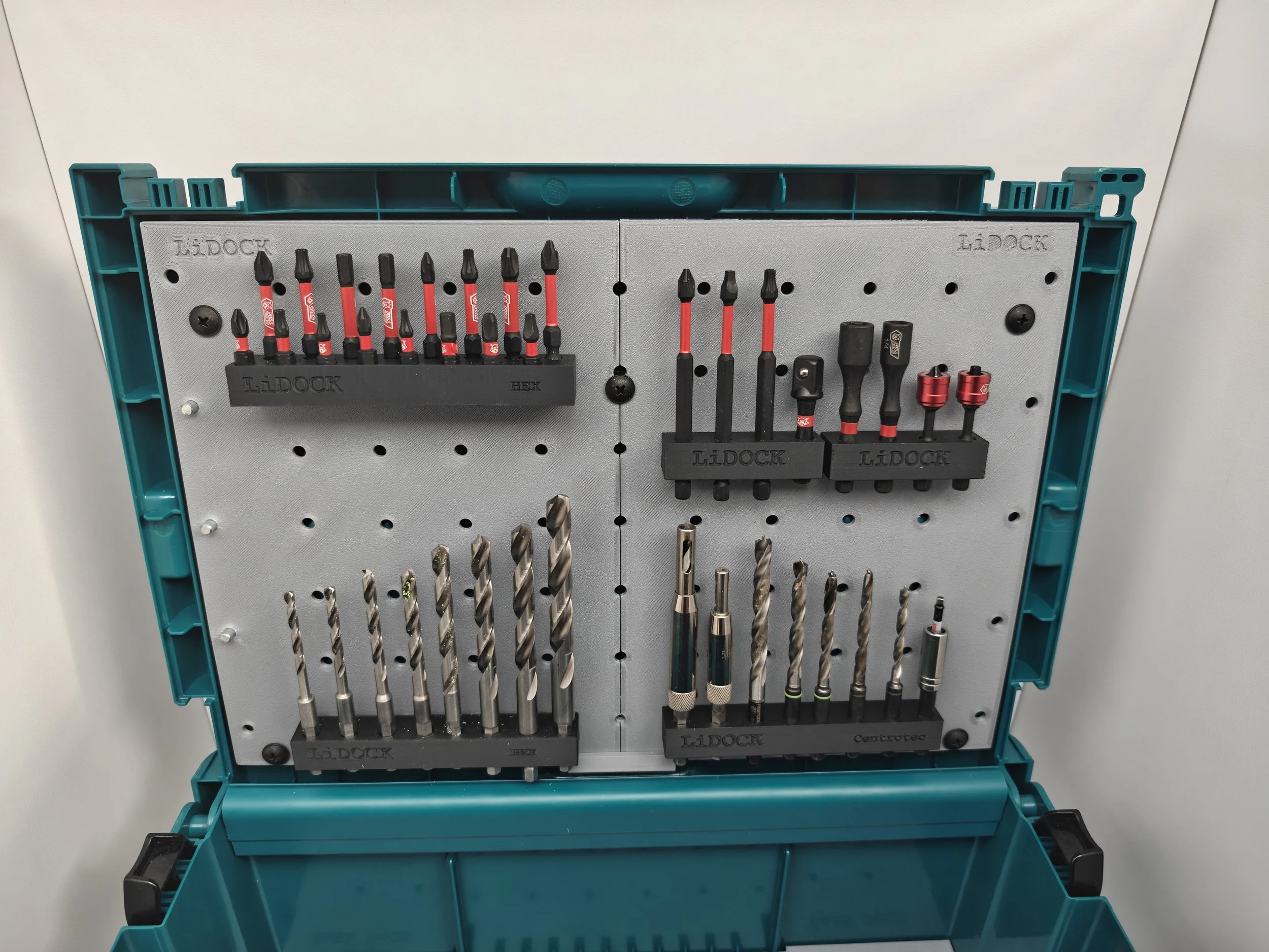 A plastic toolbox containing metal drill bits and screwdriver bits organized in black holders inside the box.