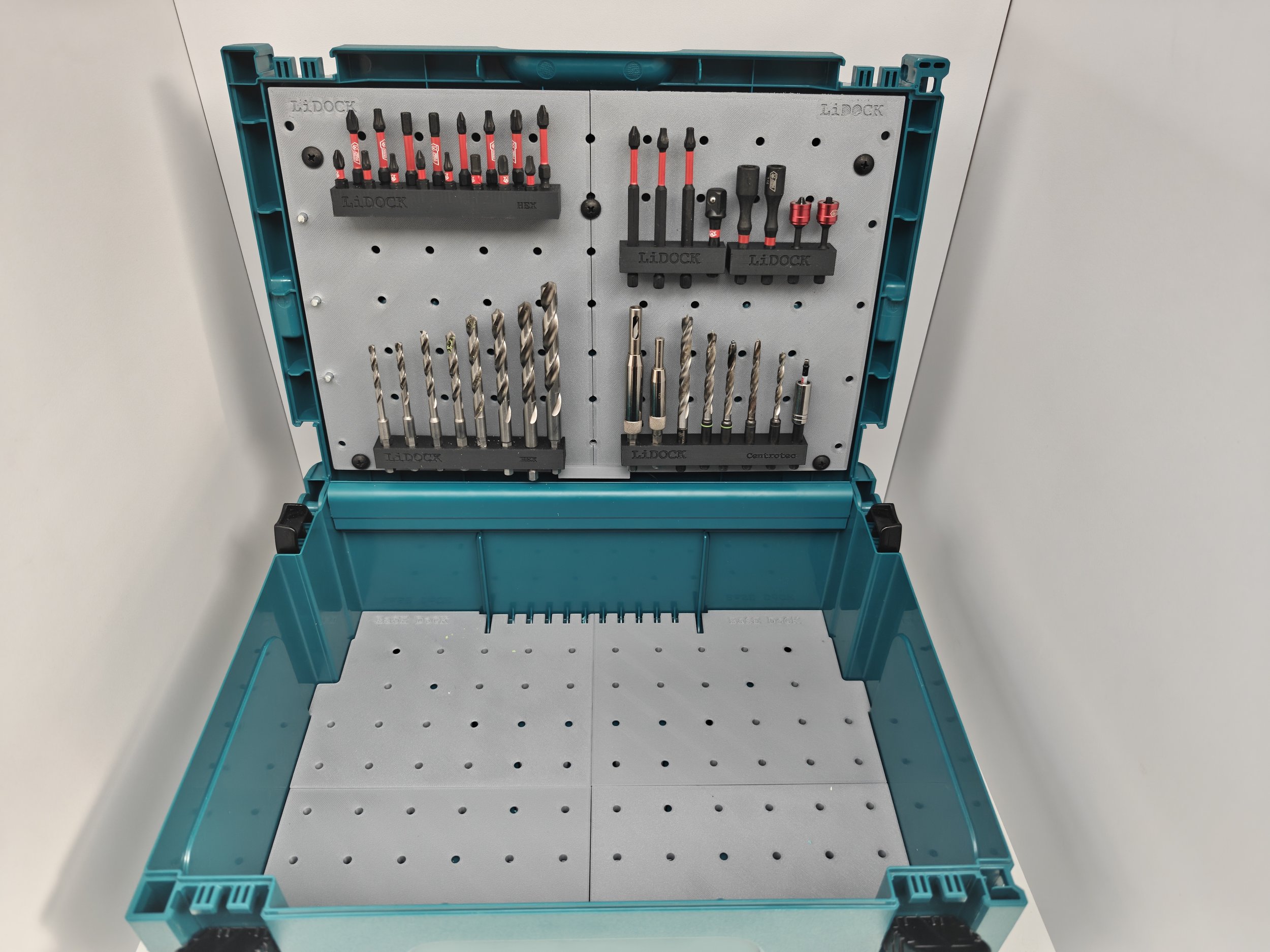 A teal toolbox with a pegboard interior holding various screwdrivers, drill bits, and small tools against a white background.
