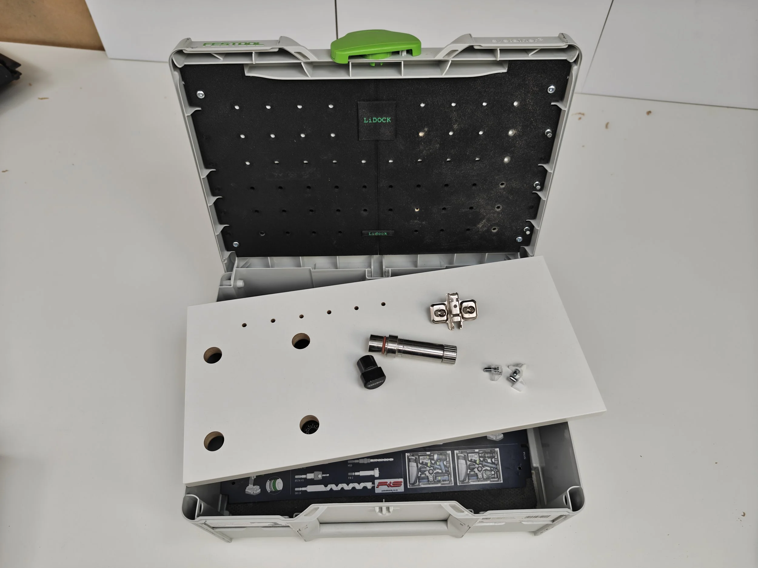 Open toolbox with tools and parts inside, on a white surface.