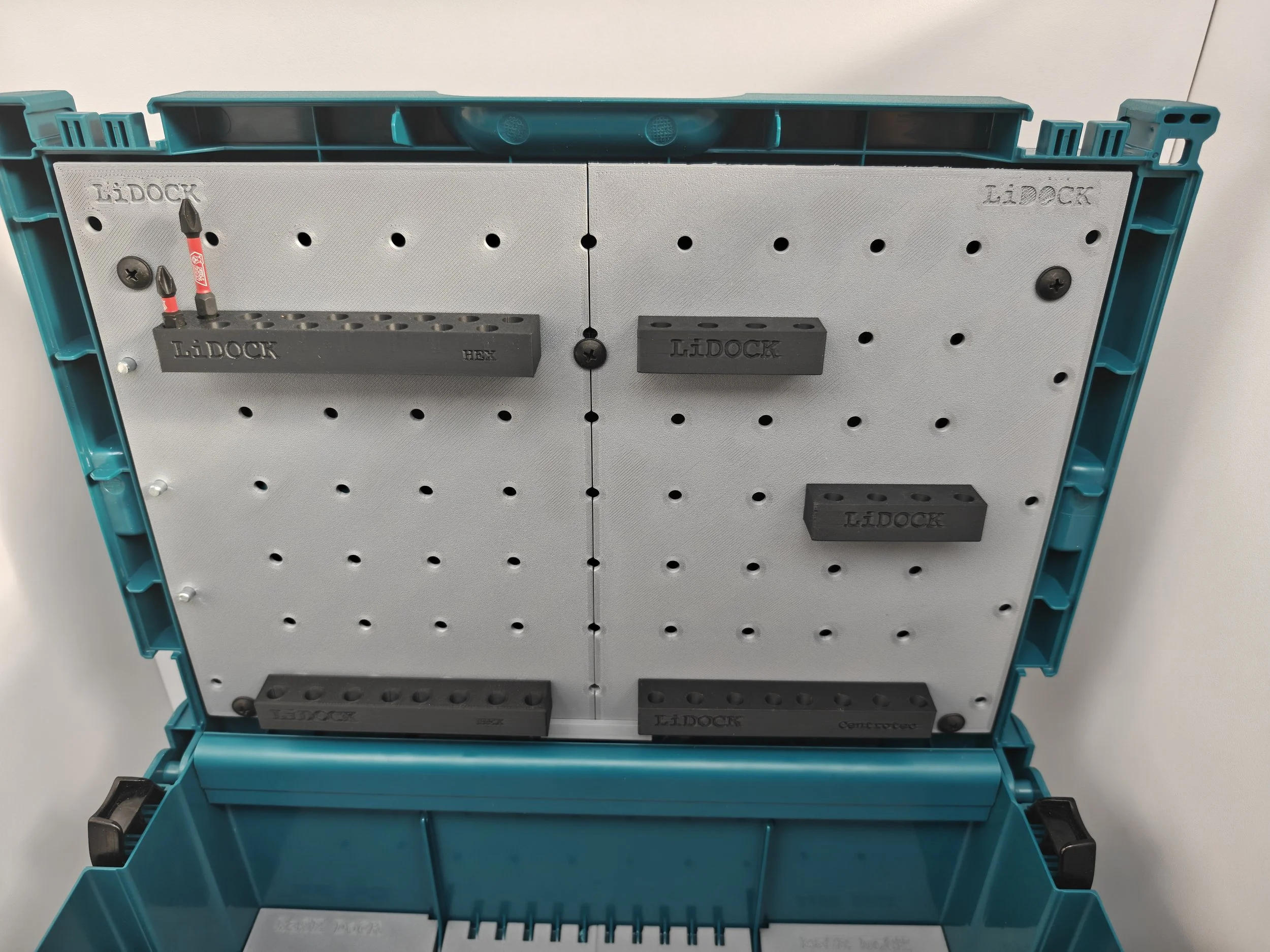 Open blue plastic toolbox with gray pegboard interior, labeled 'LI DOCK', containing various inserts and holders for tools.