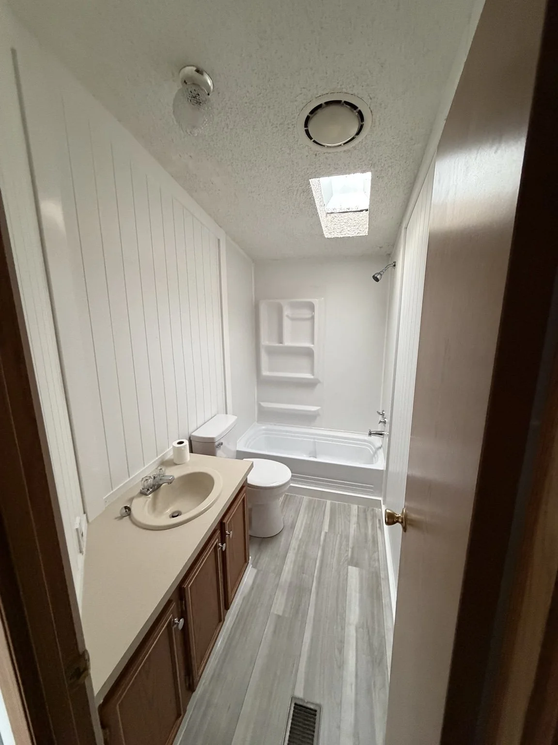 Finished Twin Lake bathroom with new flooring, white vertical wall panels, trim and refreshed tub surround