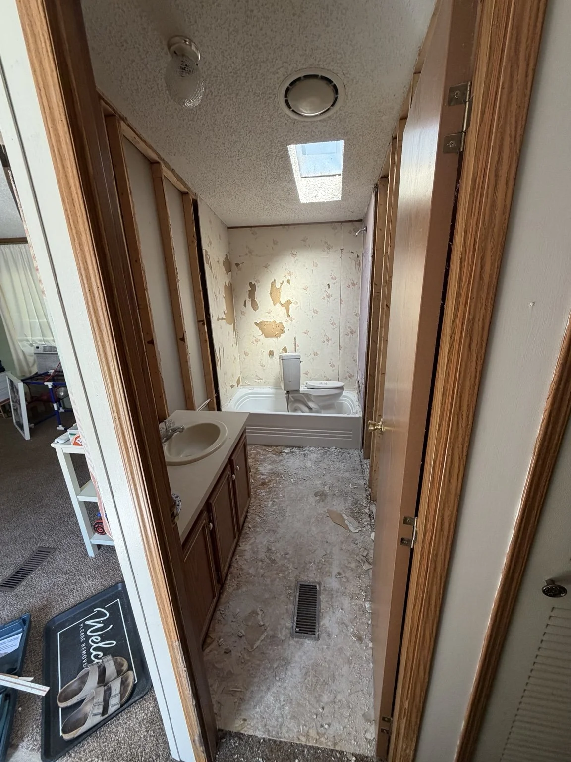 Before renovation: narrow Twin Lake bathroom with wall finishes removed and subfloor exposed