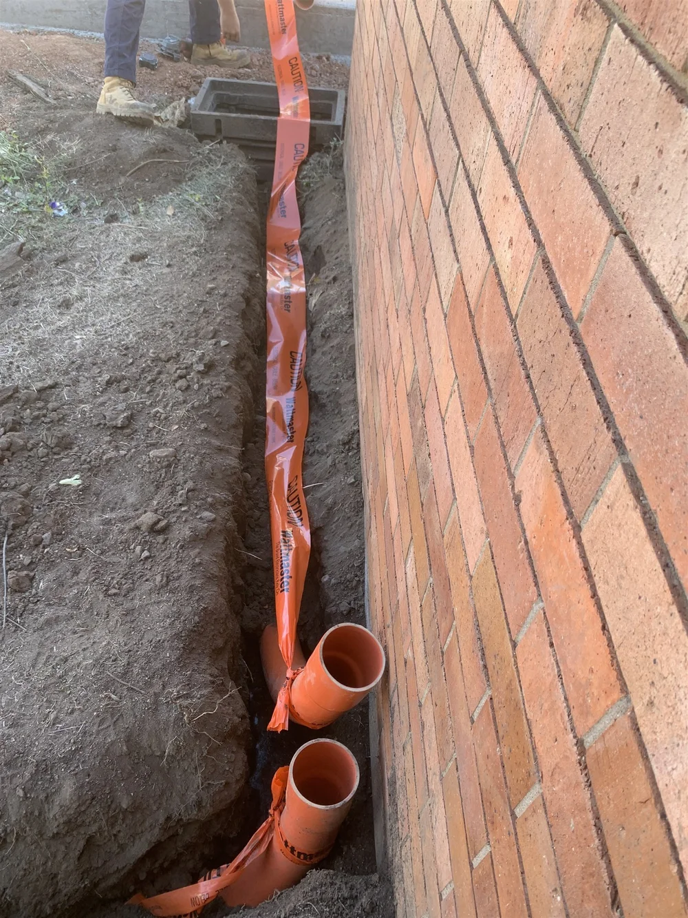 Underground conduit run beside a building