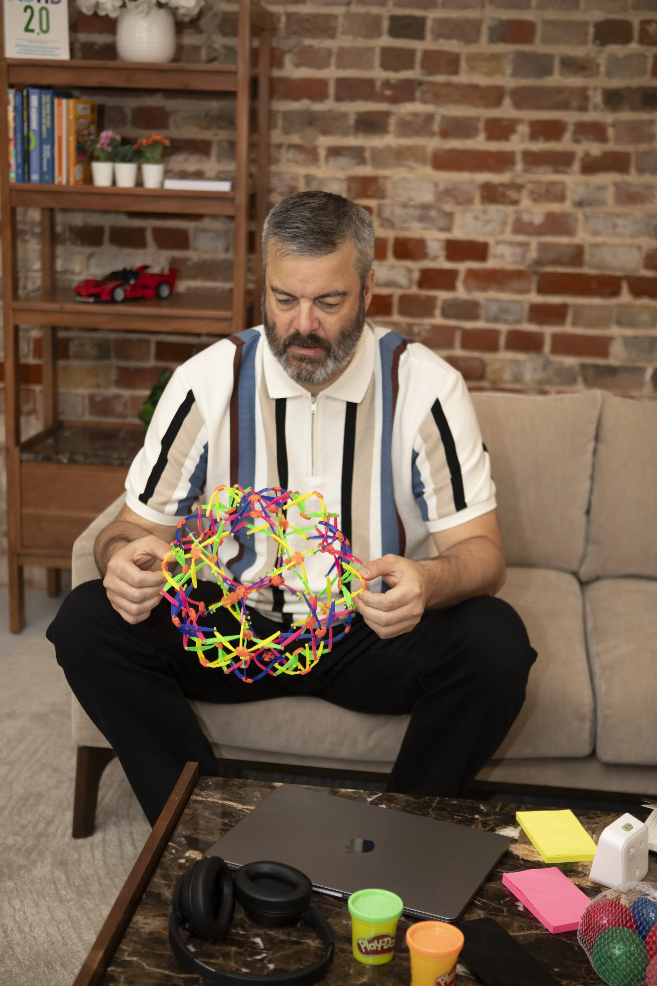 Chris, ADHD coach, holding a fidget toy with sensory tools on the table