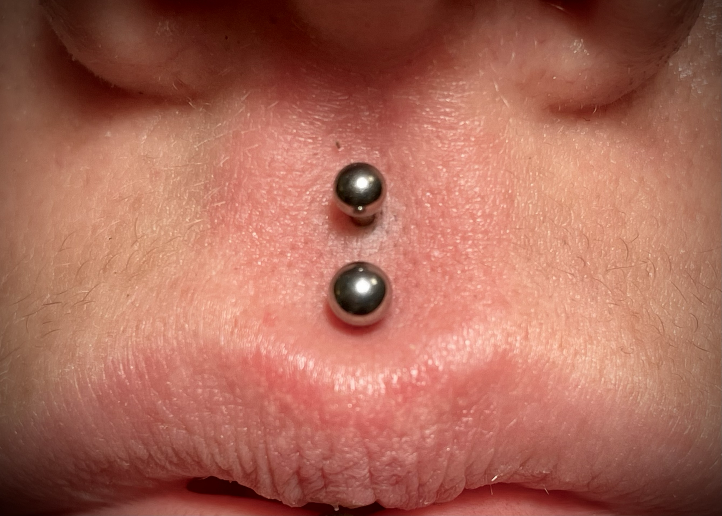Nahaufnahme eines Nasenpiercings auf der Zunft eines Menschen mit sichtbarer Zunge.