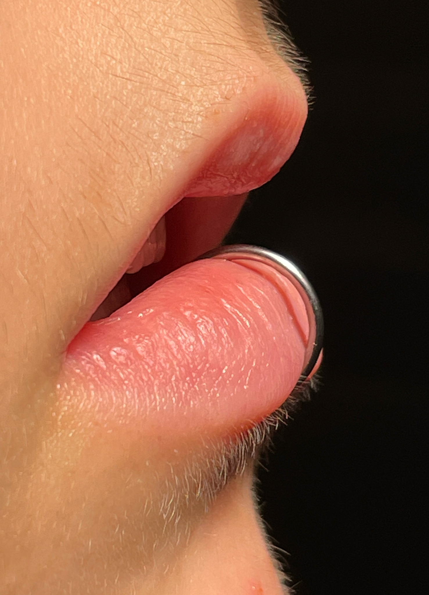 Nahaufnahme eines menschlichen Gesichts mit Fokus auf die Lippen, Nase und Kinn, schwarzen Hintergrund.