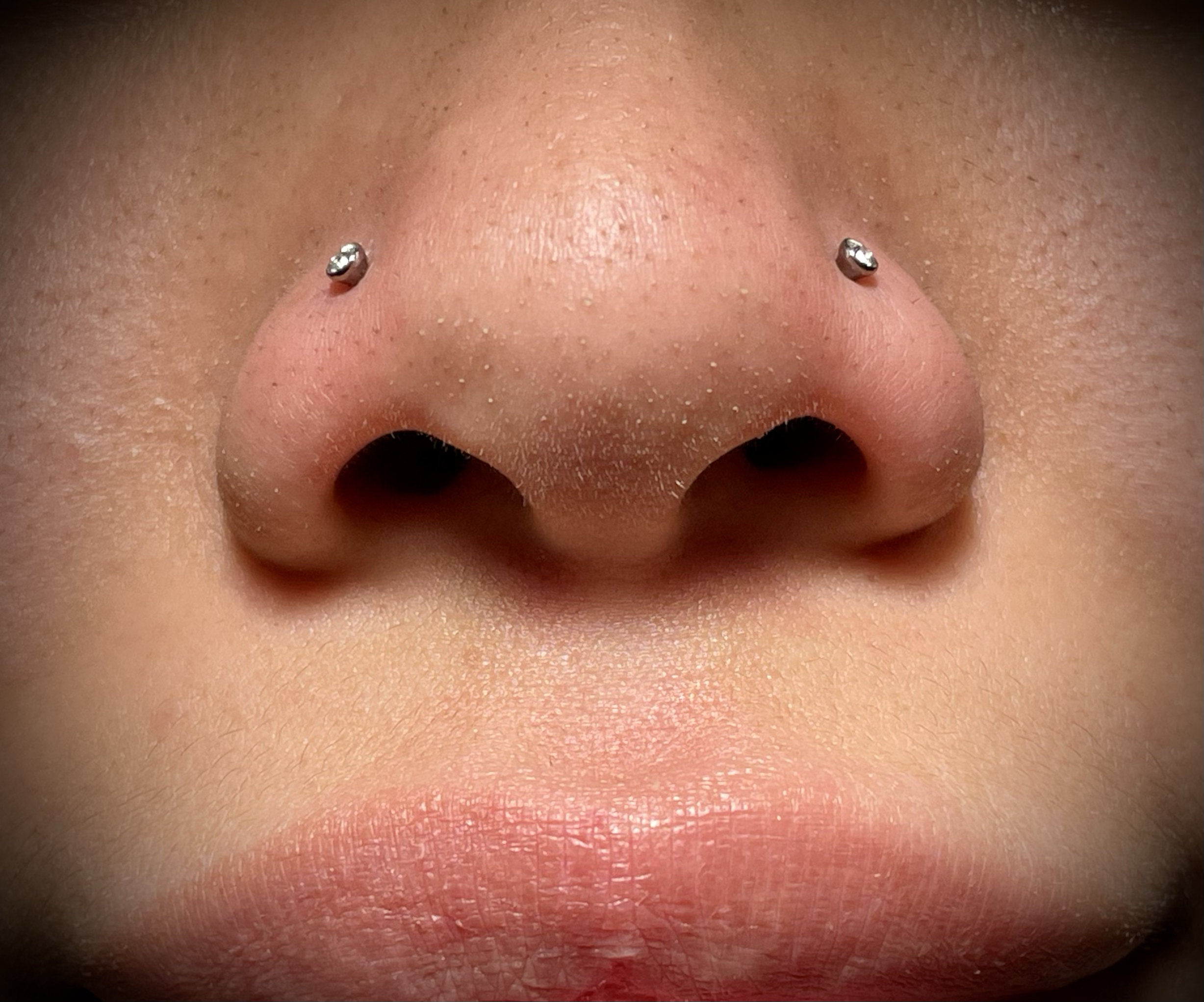 Nahaufnahme eines menschlichen Nasenloches mit Metall-Nasenpiercing.