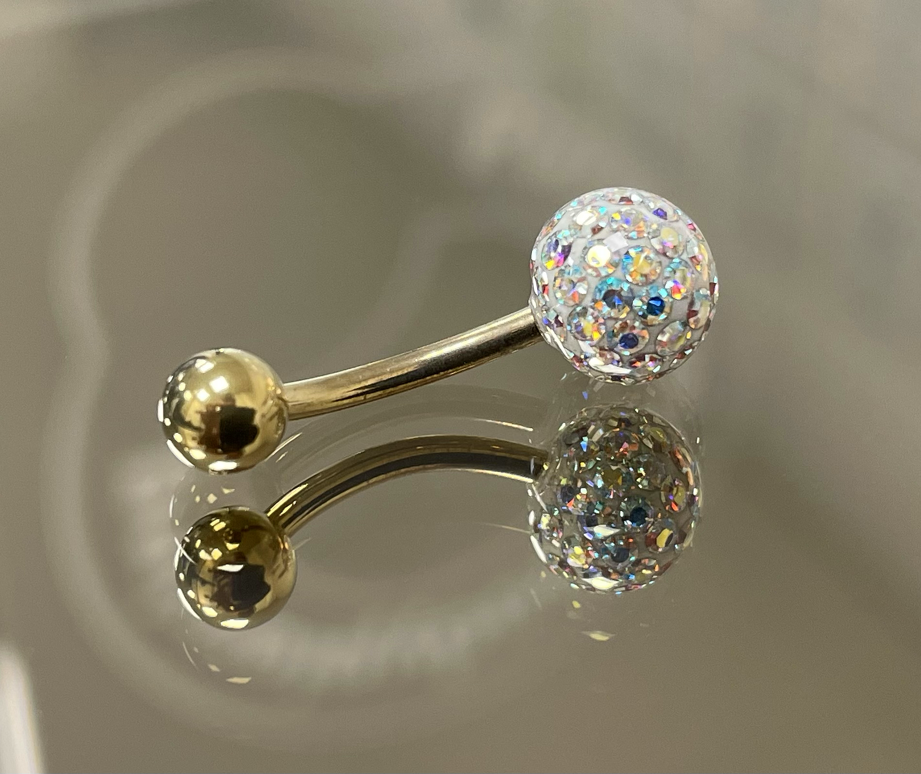 Nahaufnahme eines Nasen-Piercings mit einer großen, mit Kristallen bedeckten Kugel, die an einem goldfarbenen Draht befestigt ist.