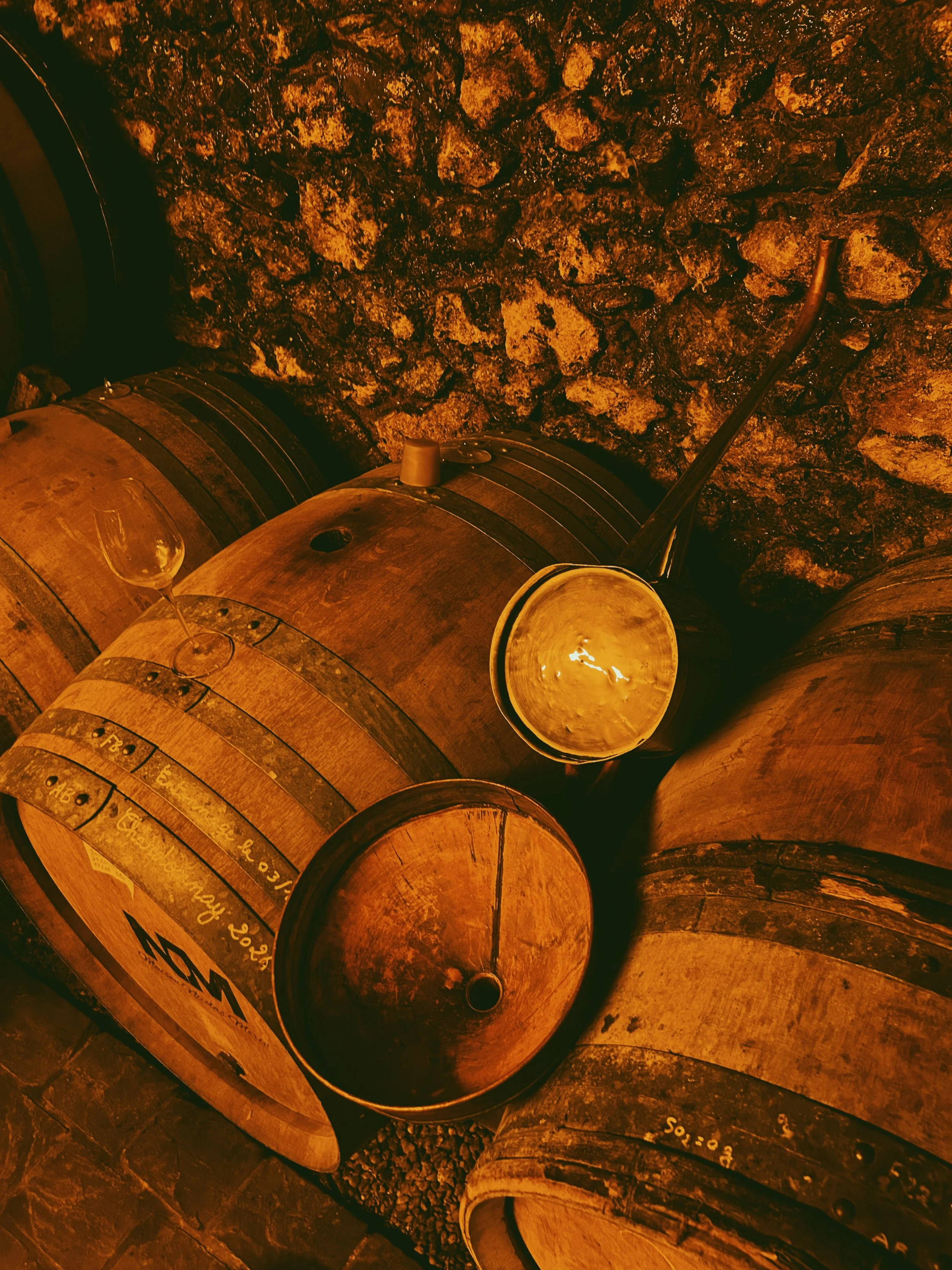 Les tonneaux en bois dans une cave. Une bougie allumée et un verre à vin reposent sur un tonneau.