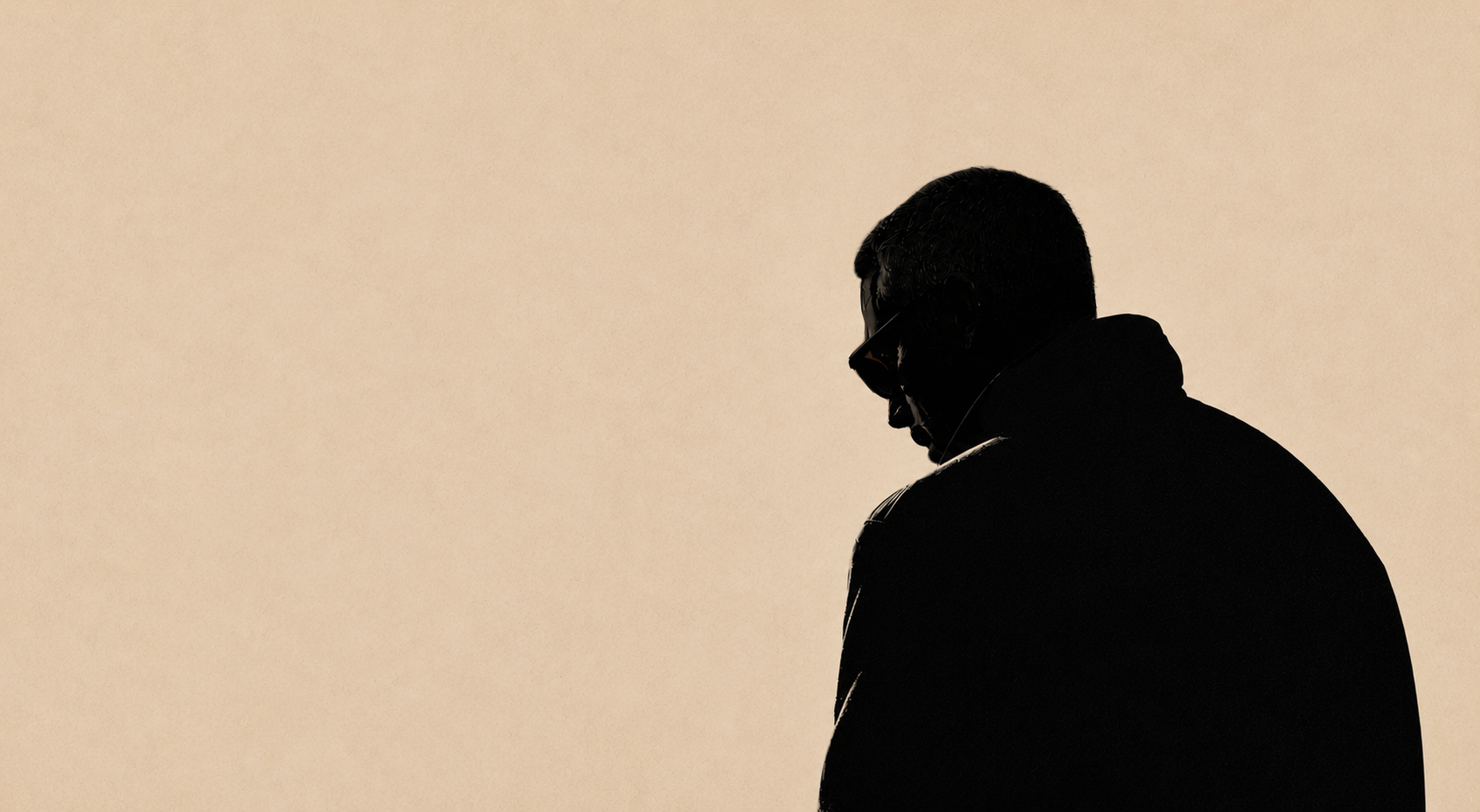 Silhouette of a man with glasses looking down against a light beige background.