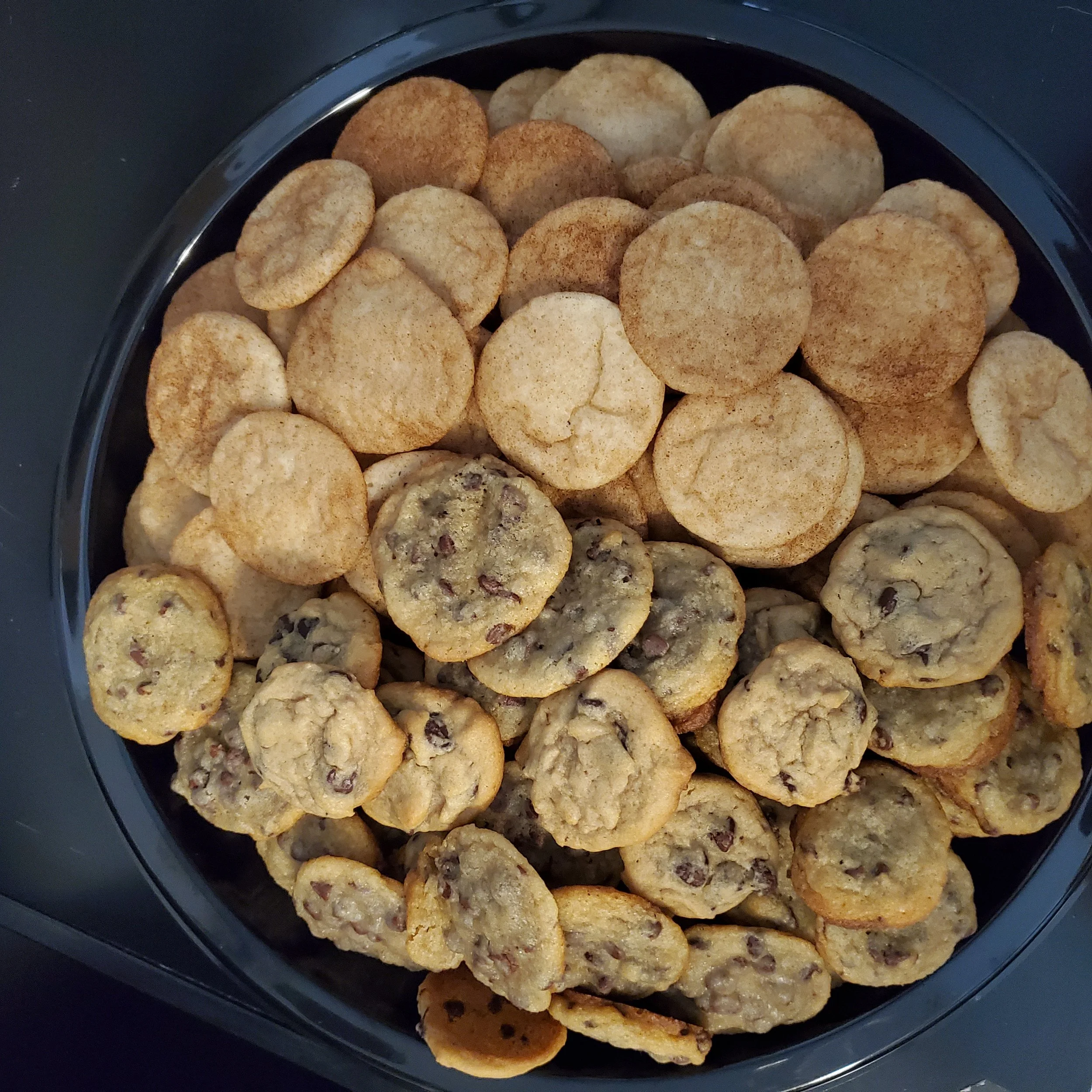 Collection of assorted cookies in a black container, including chocolate chip, oatmeal raisin, and sugar cookies.