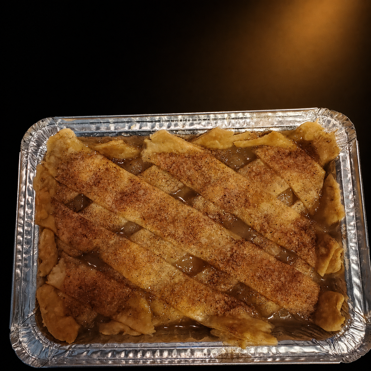 Baked apple pie with lattice crust in a foil tray.