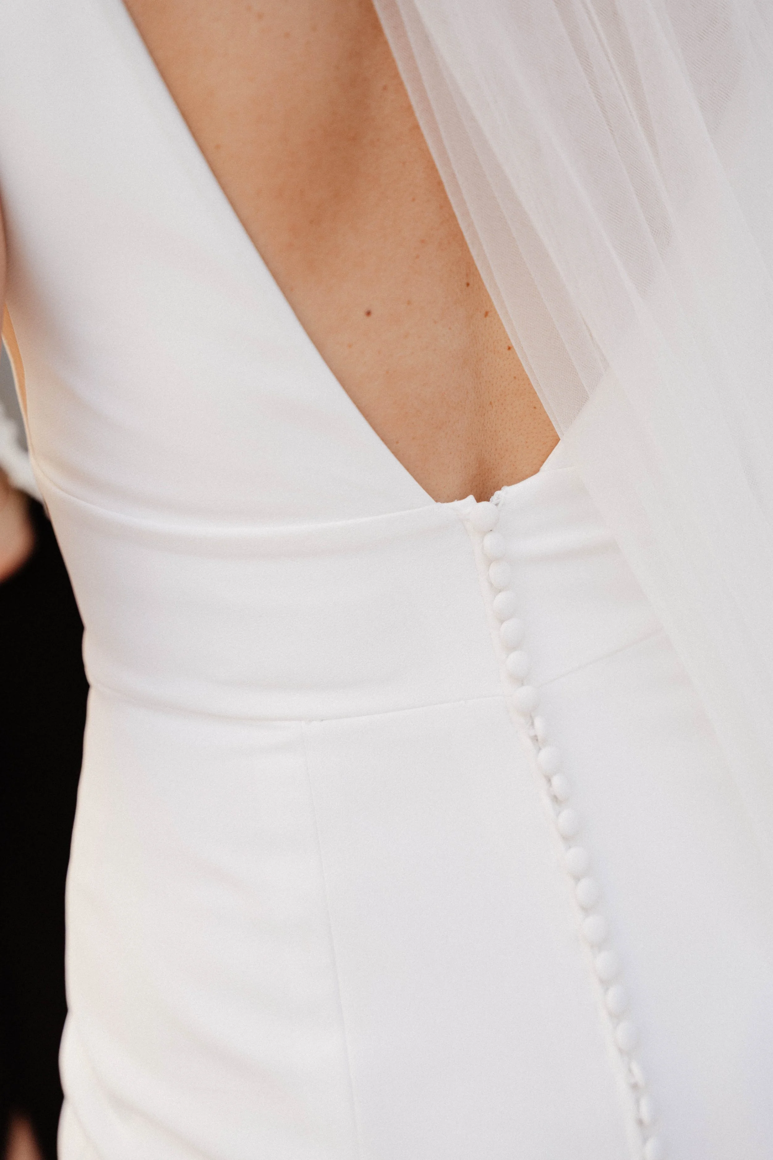 Zoom sur la couture d'une robe blanche élégante avec des boutons et un tissu transparent dans la partie supérieure.