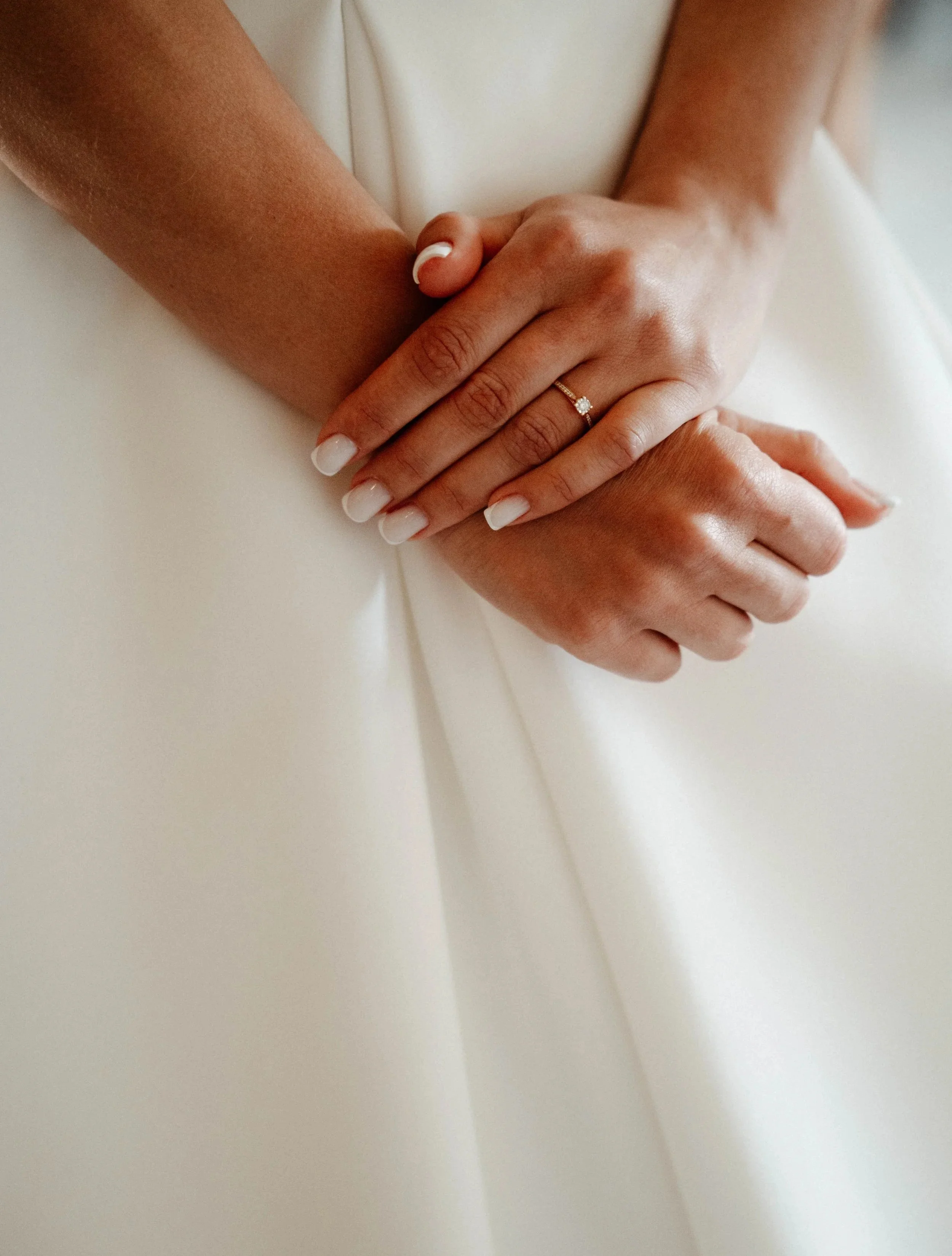 Deux mains croisée dont une avec une bague en diamant, sur un fond blanc