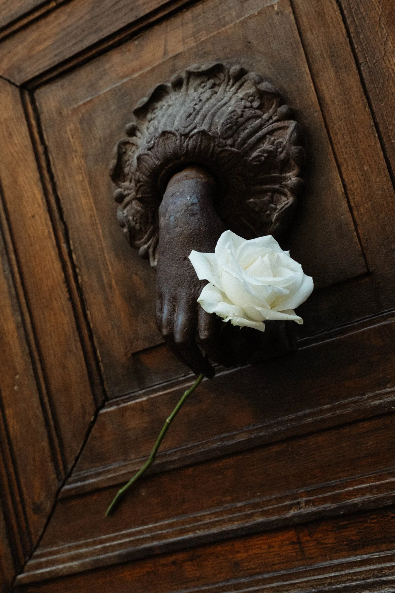 Une pièce de mobilier en bois avec une décoration en relief en forme de motif floral, un bouton en métal et une fleur blanche en boutonnière.