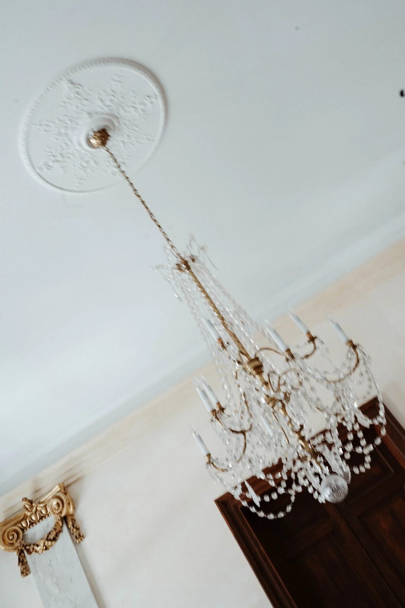 Un lustre en cristal suspendu dans un salon élégant avec un décor classique, comprenant un miroir doré sur le mur.