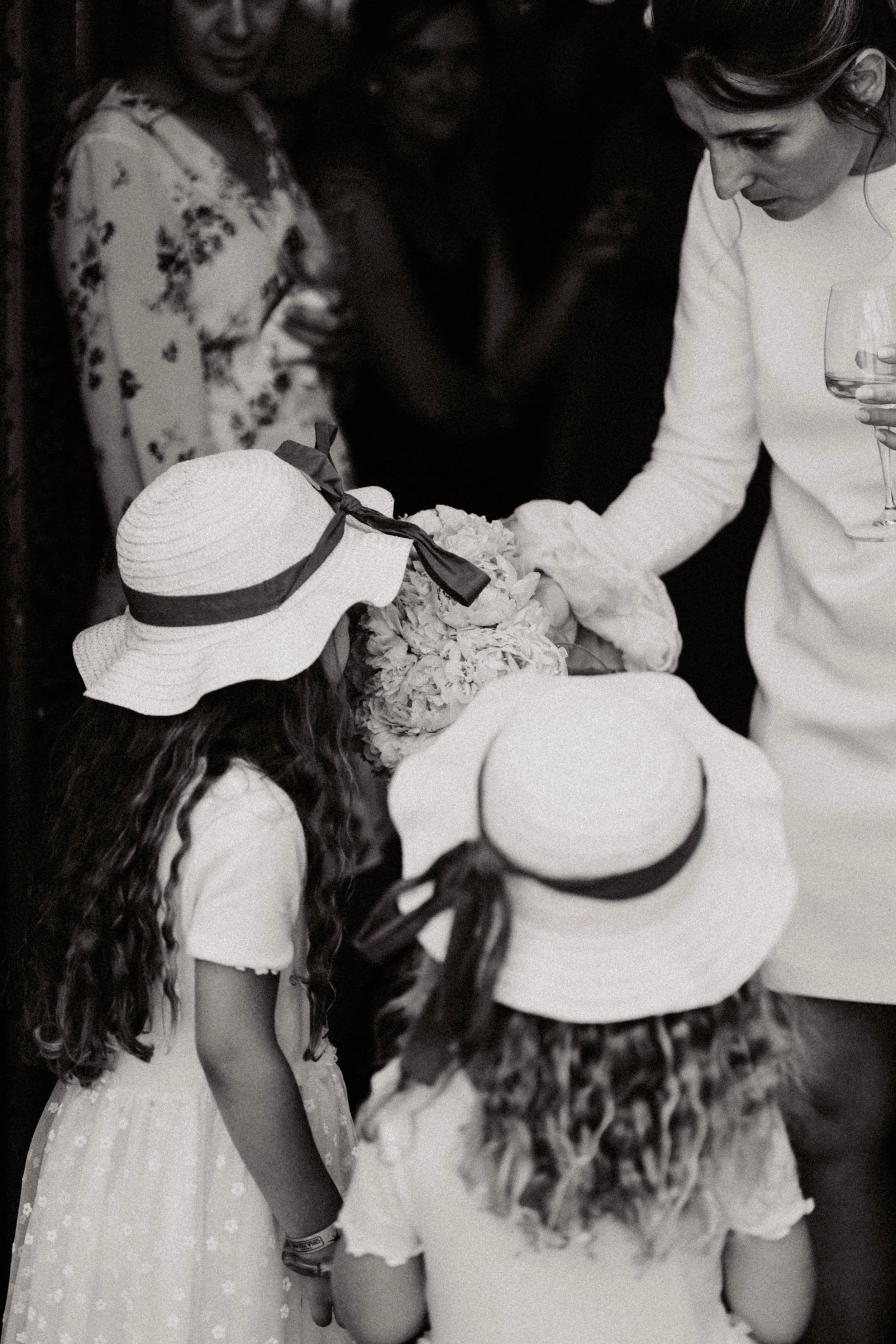Groupe de jeunes filles en vêtements d'été et chapeaux, regardant un objet décoratif avec des fleurs, lors d'une occasion spéciale.
